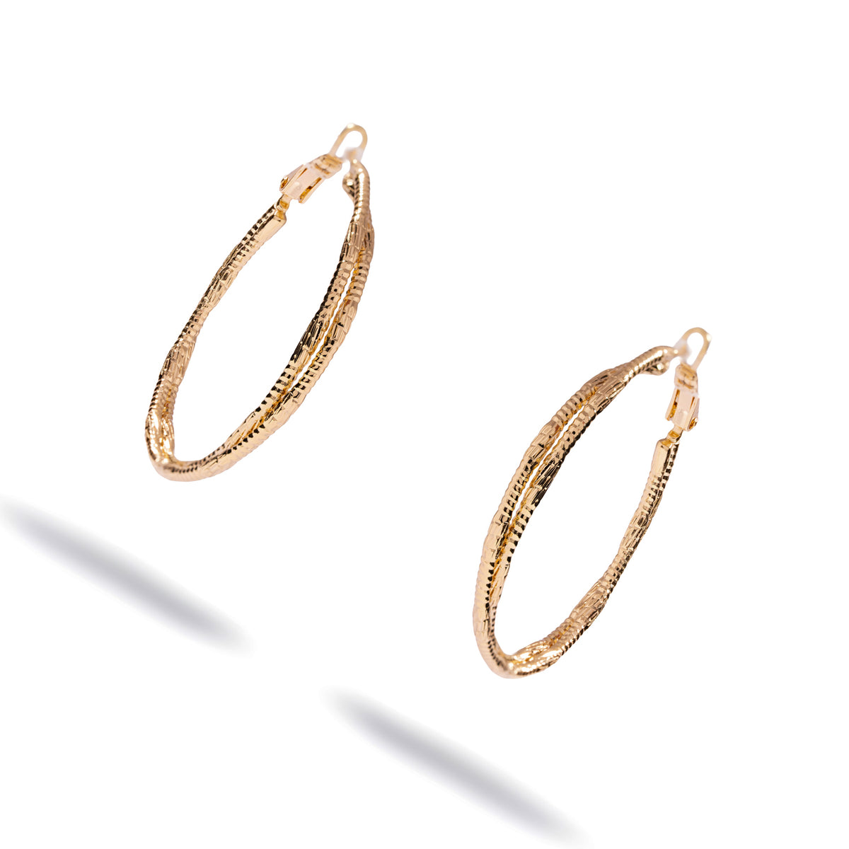 Angled studio view of the twisted gold hoop earrings showing the ridged surface and the hinged hoop closure