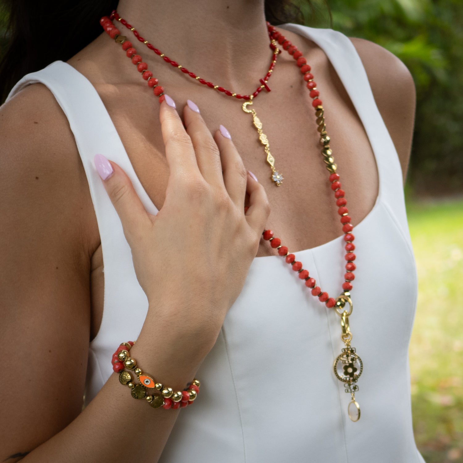 Close-up of 18K gold-plated evil eye bead and engraved shell symbol charms

