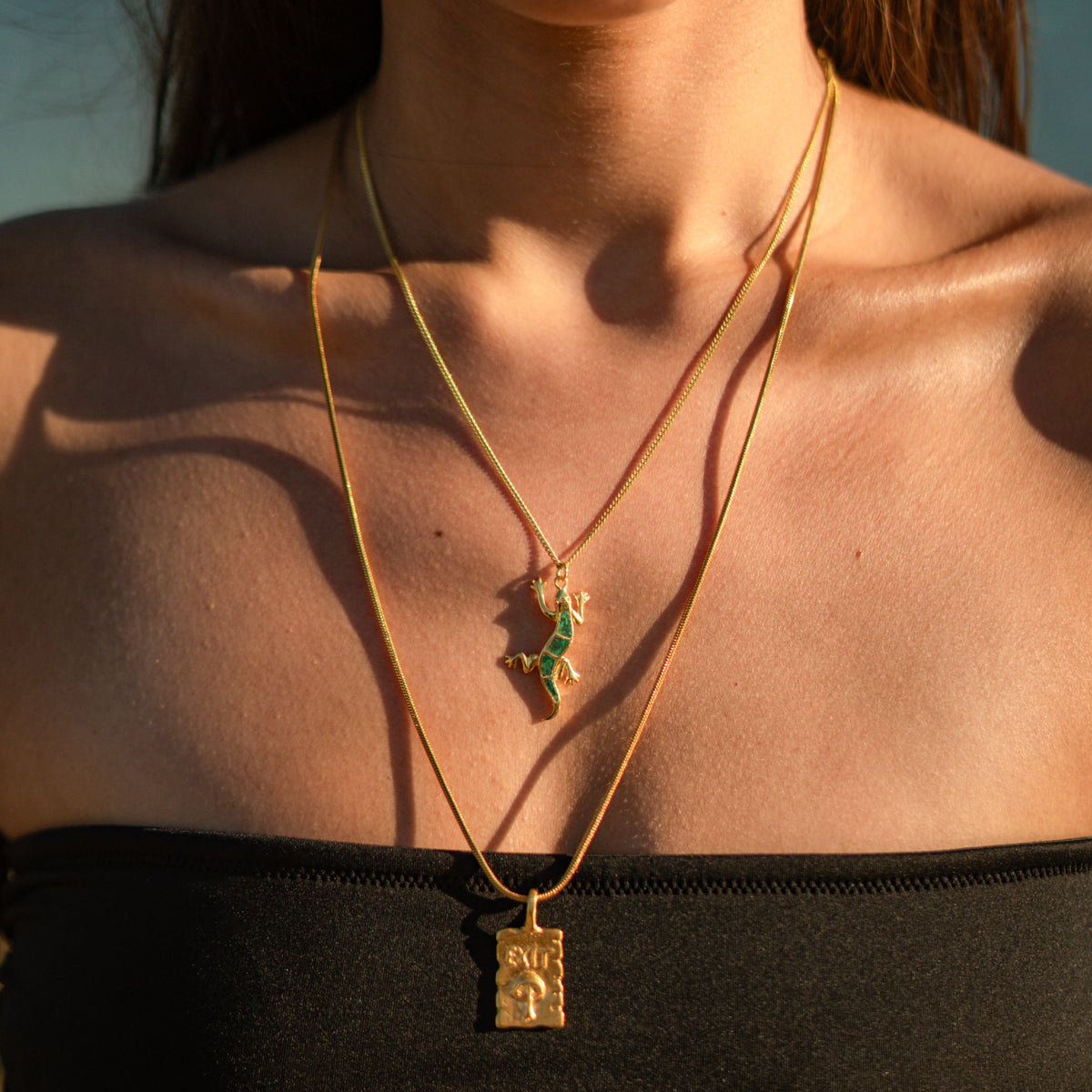 Find Your Way Exit Engraved Gold Pendant Necklace layered with a shorter green gecko pendant necklace