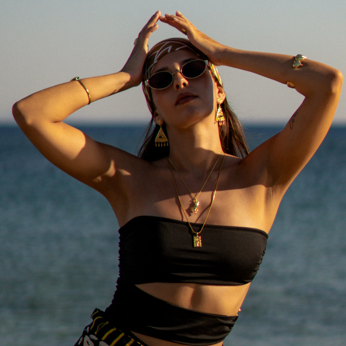 Model with raised arms wearing the Find Your Way Exit Engraved Gold Pendant Necklace on a long chain