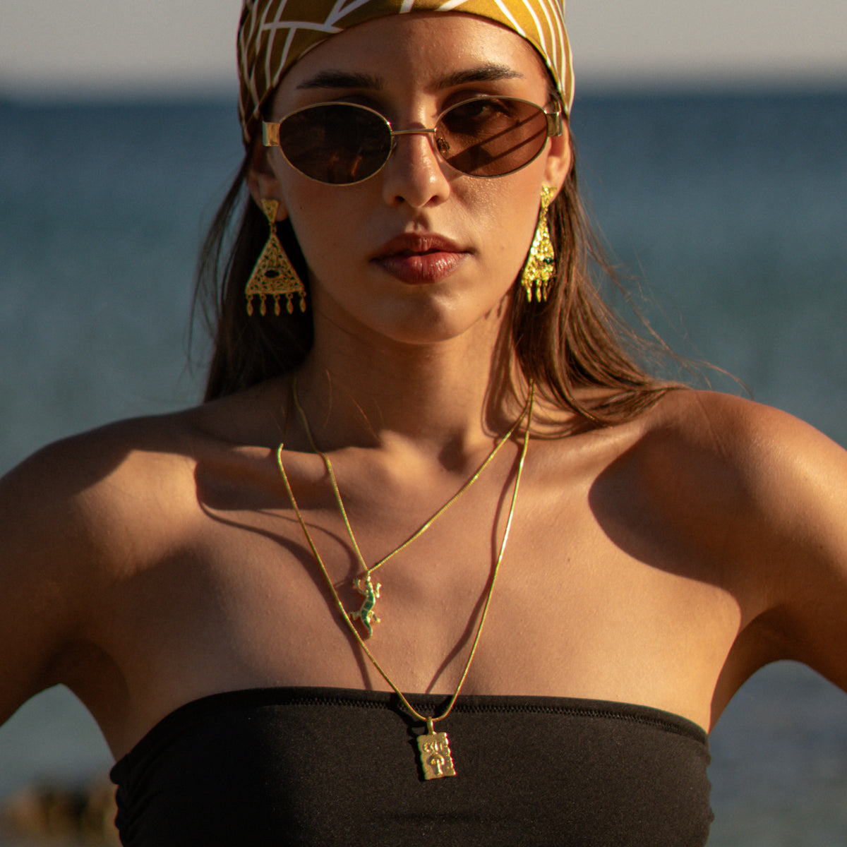 Front view of the model wearing the Find Your Way Exit Engraved Gold Pendant Necklace with gold statement earrings