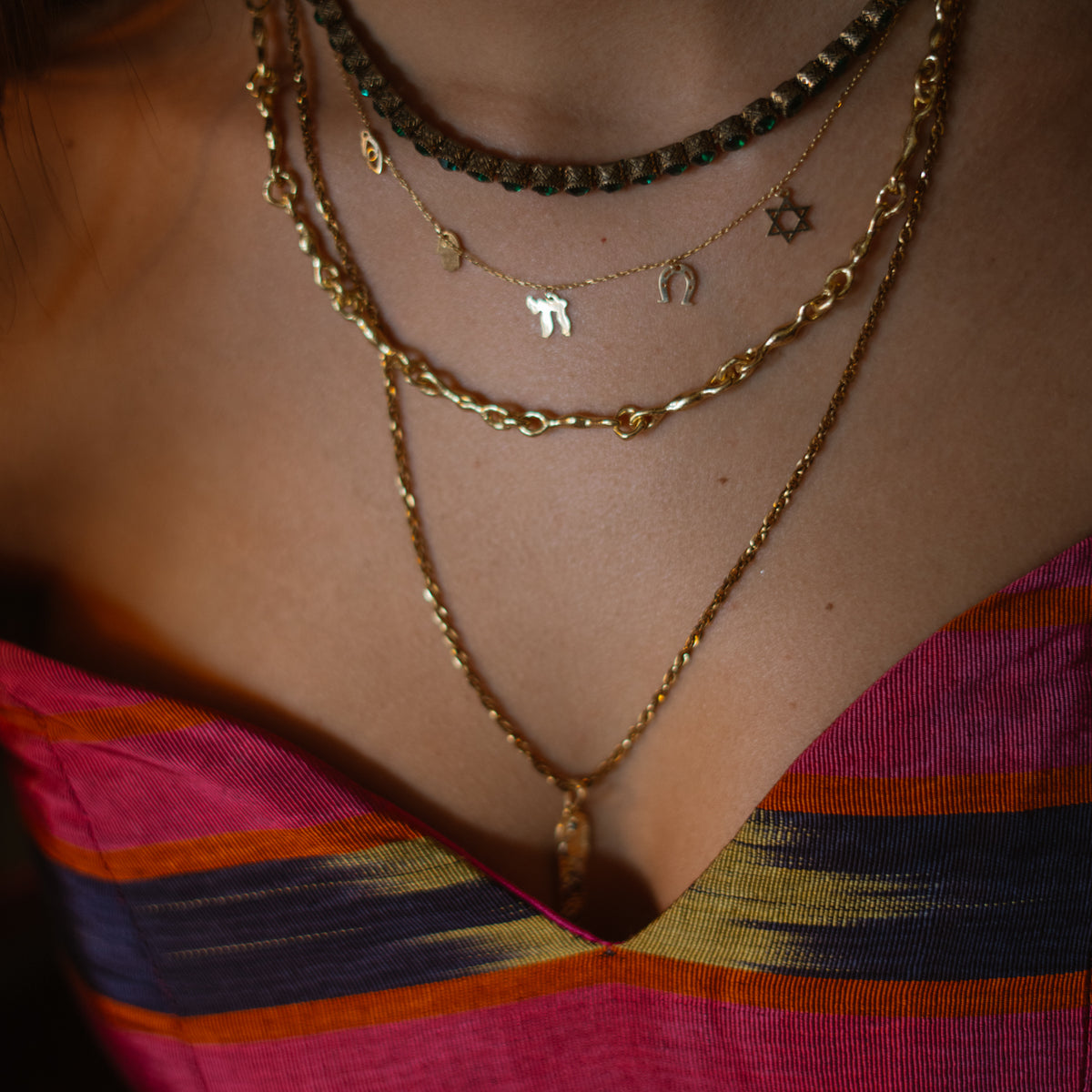 Five Guardians gold charm necklace layered under the Emerald Antique Gold Tennis Mystic Necklace with gold chains