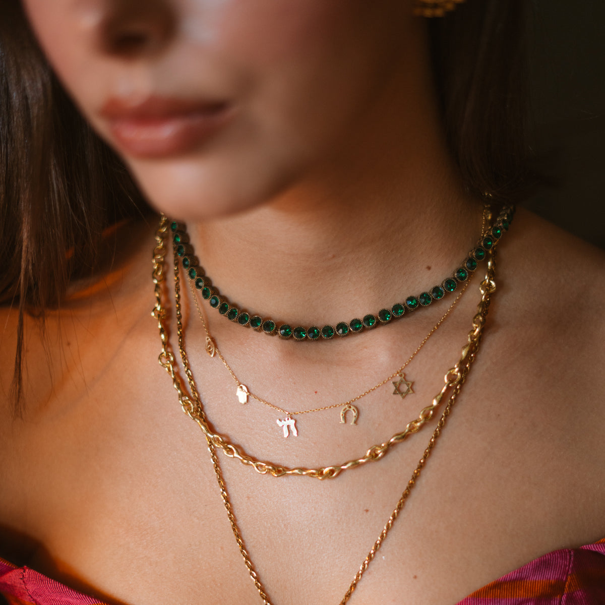 Close view of the Five Guardians charms worn at the collarbone below the Emerald Antique Gold Tennis Mystic Necklace