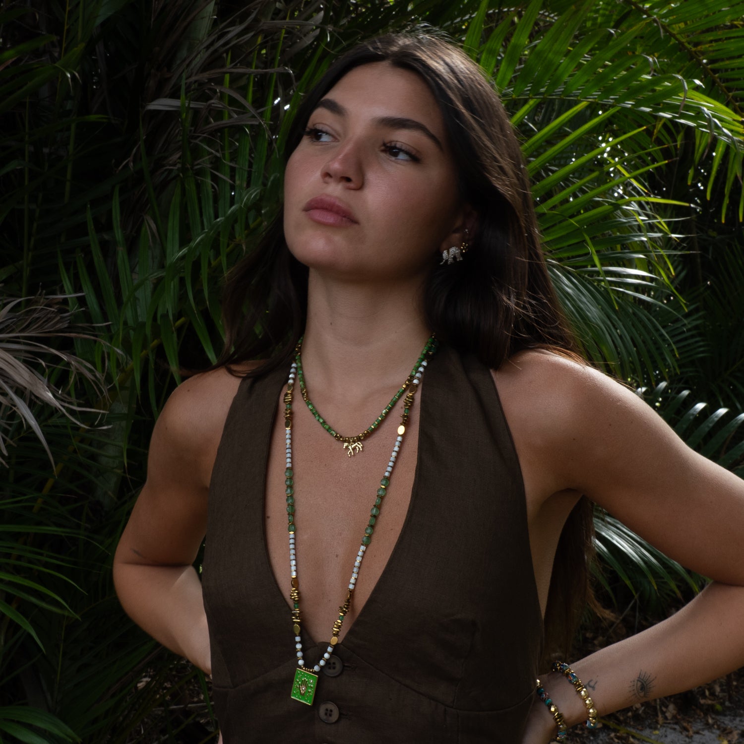 Layered necklace look with green beaded choker and long talisman necklace in green and gold palette