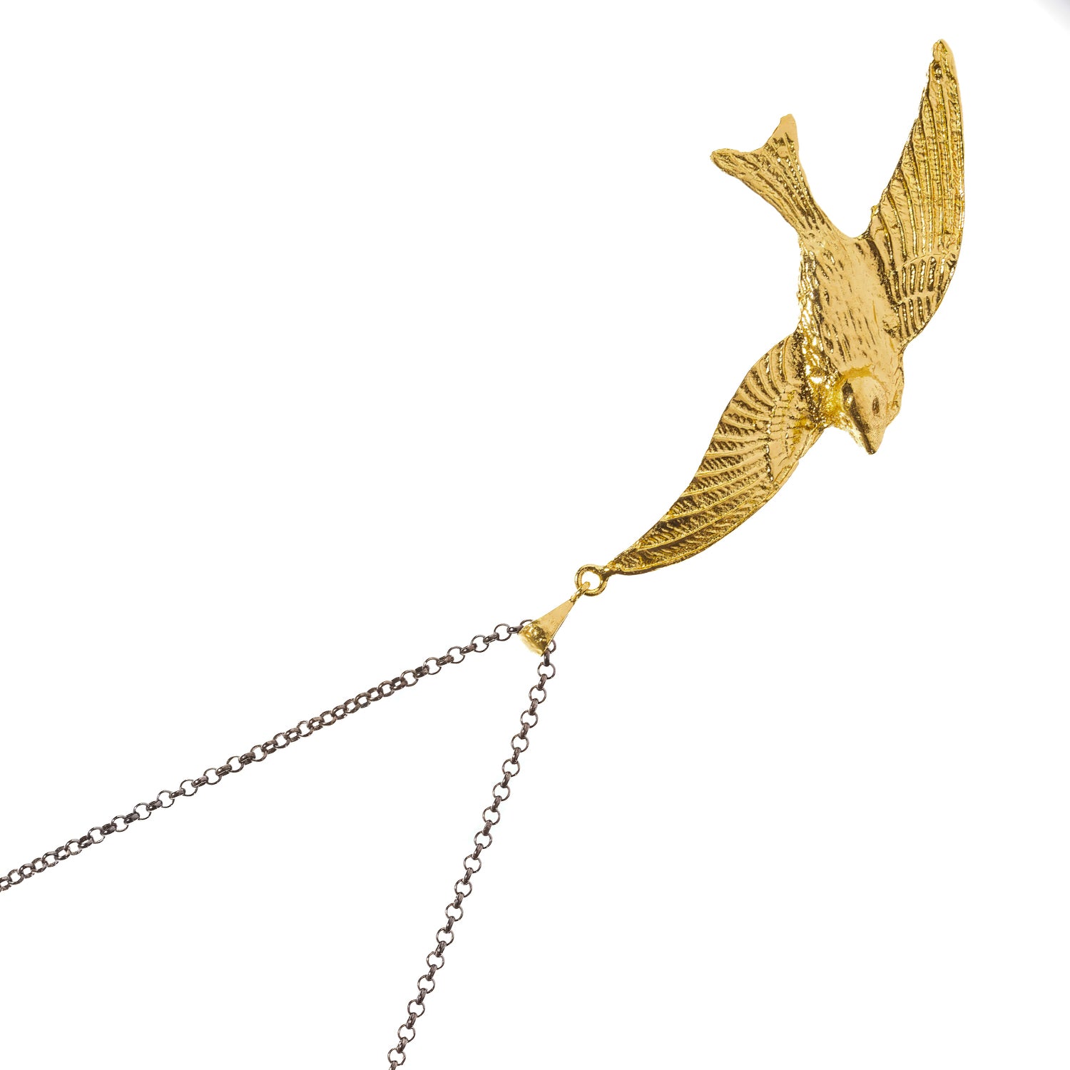 Close view of the gold sparrow pendant showing the hand scored feather detail and swept wings
