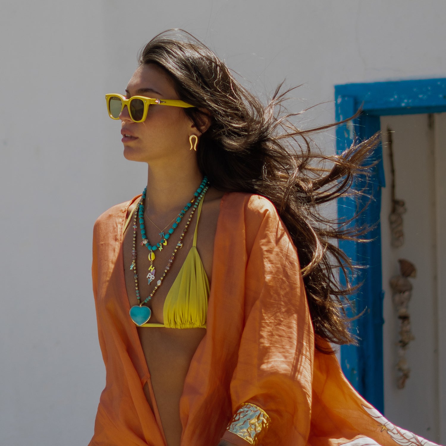 Model in profile wearing the Golden Horseshoe stud earrings with hair blowing in the wind, coastal backdrop