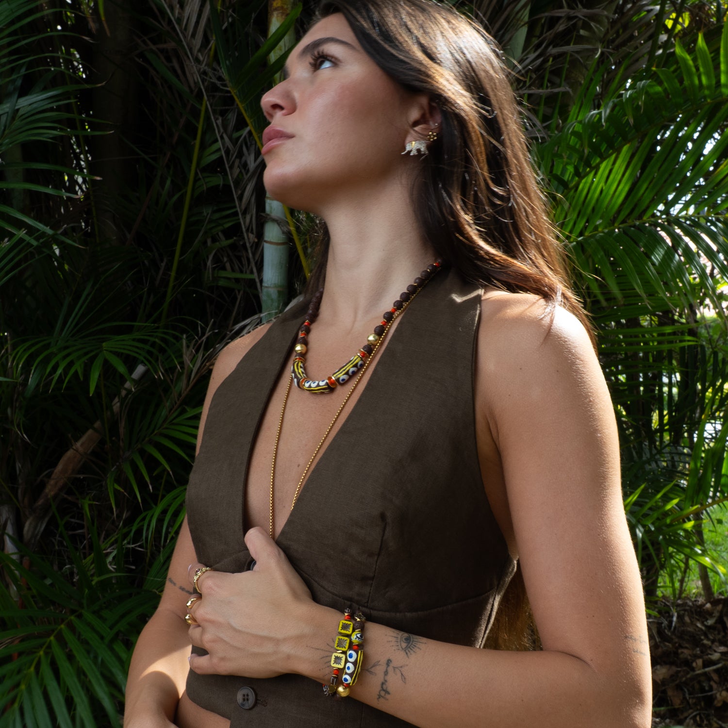 Woman wearing handmade evil eye bracelet pair with yellow and brown ceramic evil eye beads, paired with colorful beaded necklace
