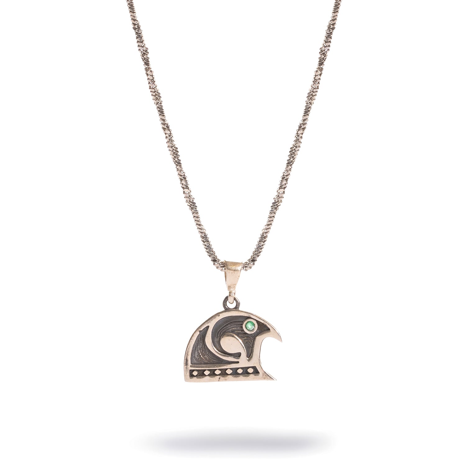 Close view of the Guardian Falcon pendant showing the engraved falcon head, oxidized silver detailing and emerald eye