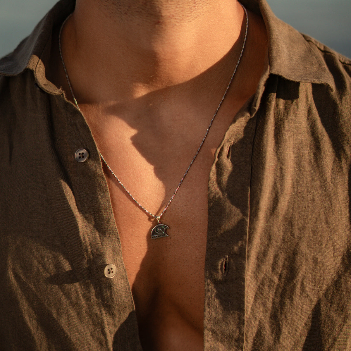Guardian Falcon Emerald Eye Silver Men's Necklace worn on the chest, pendant resting over an open linen collar