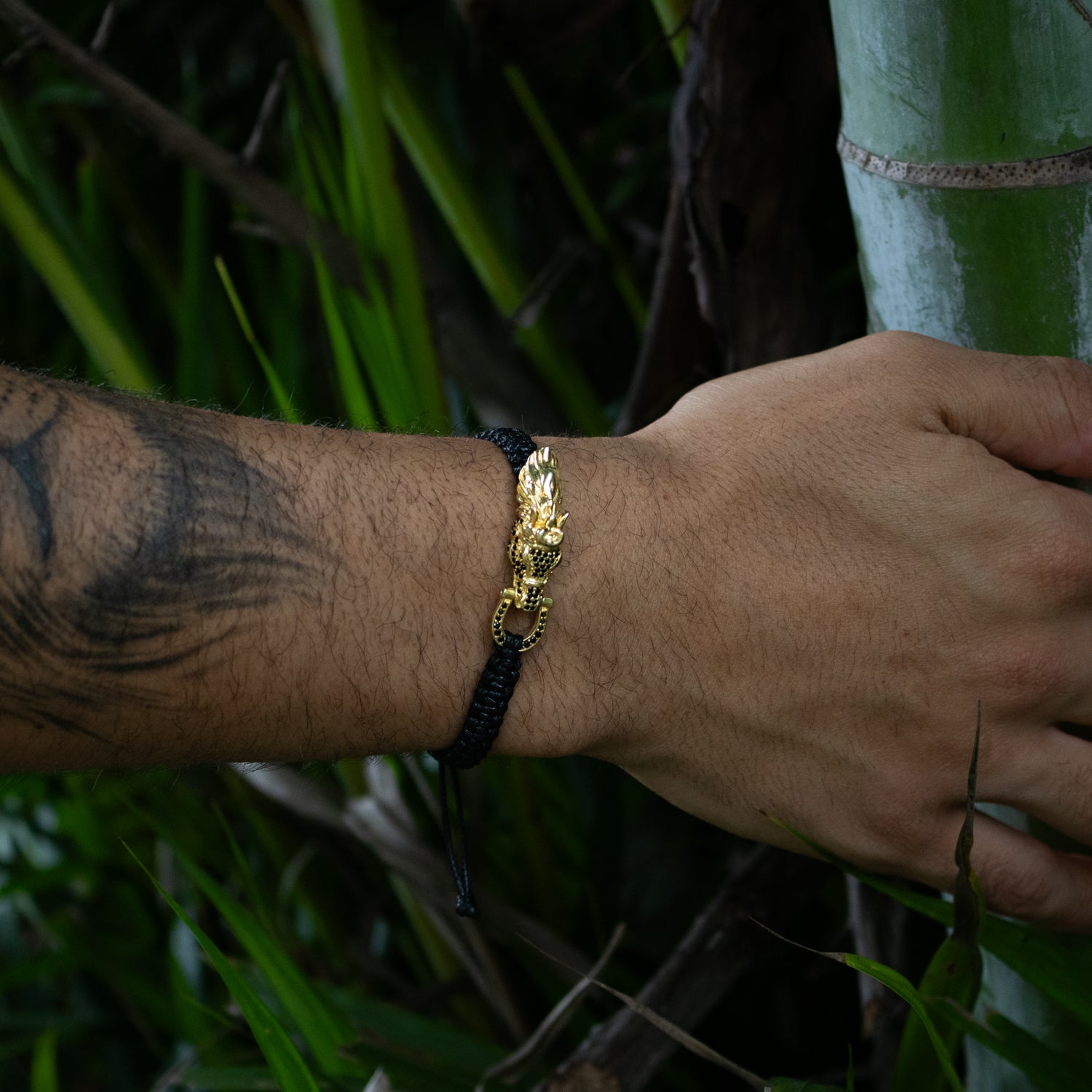 Black woven bracelet with adjustable cord, 24K gold-plated sterling silver guardian lion centerpiece, black CZ diamond detail, bold style.