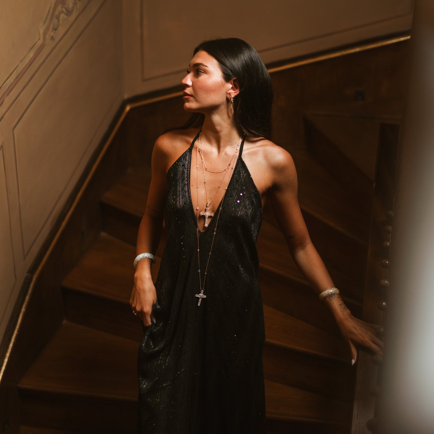 Full length view of a woman wearing a long gold cross statement necklace in evening light