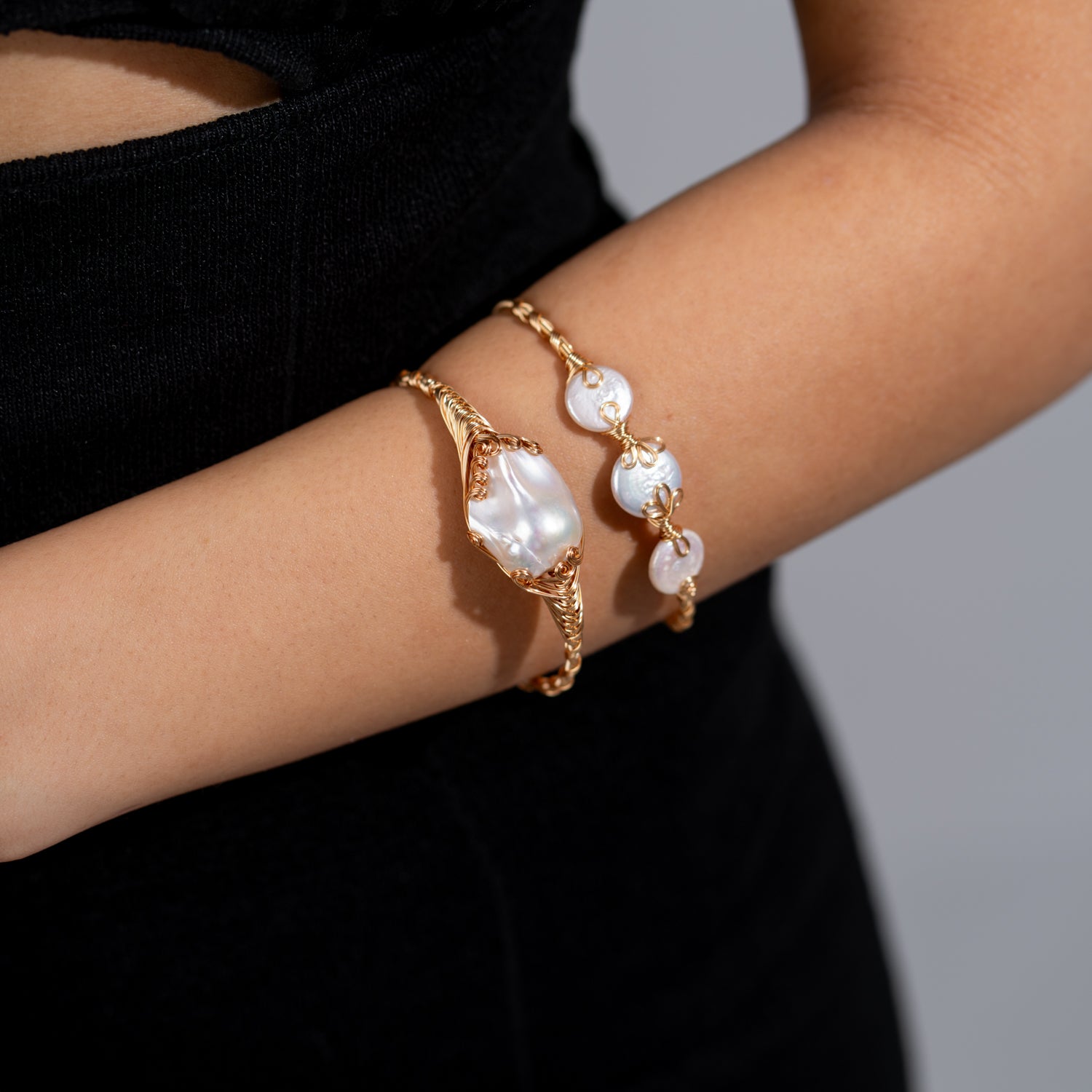 Handcrafted open cuff bracelet with organic baroque pearls wrapped in 18K gold-plated wire on an adjustable gold band.
