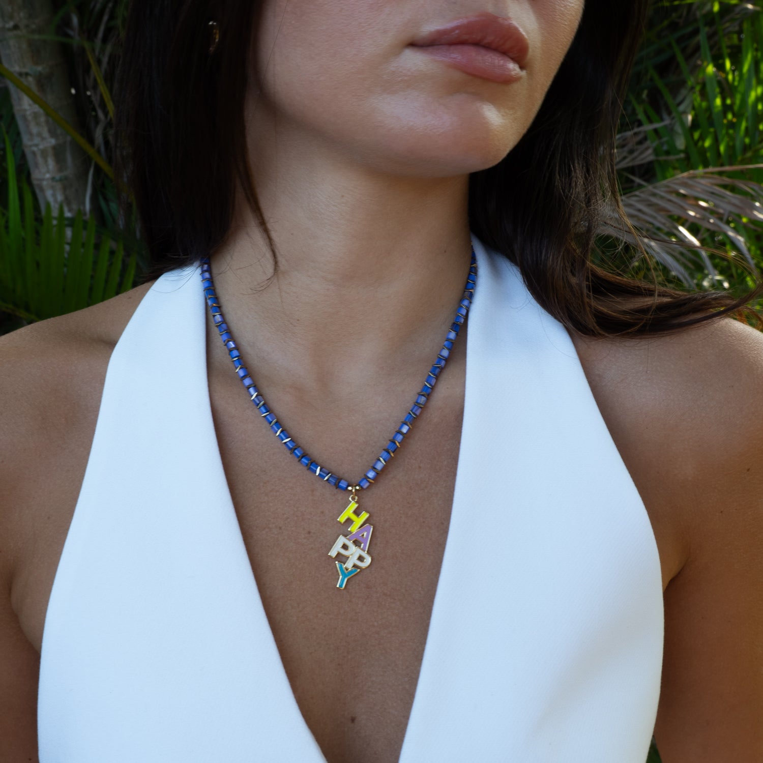 Woman wearing happy enamel pearl necklace with white halter top