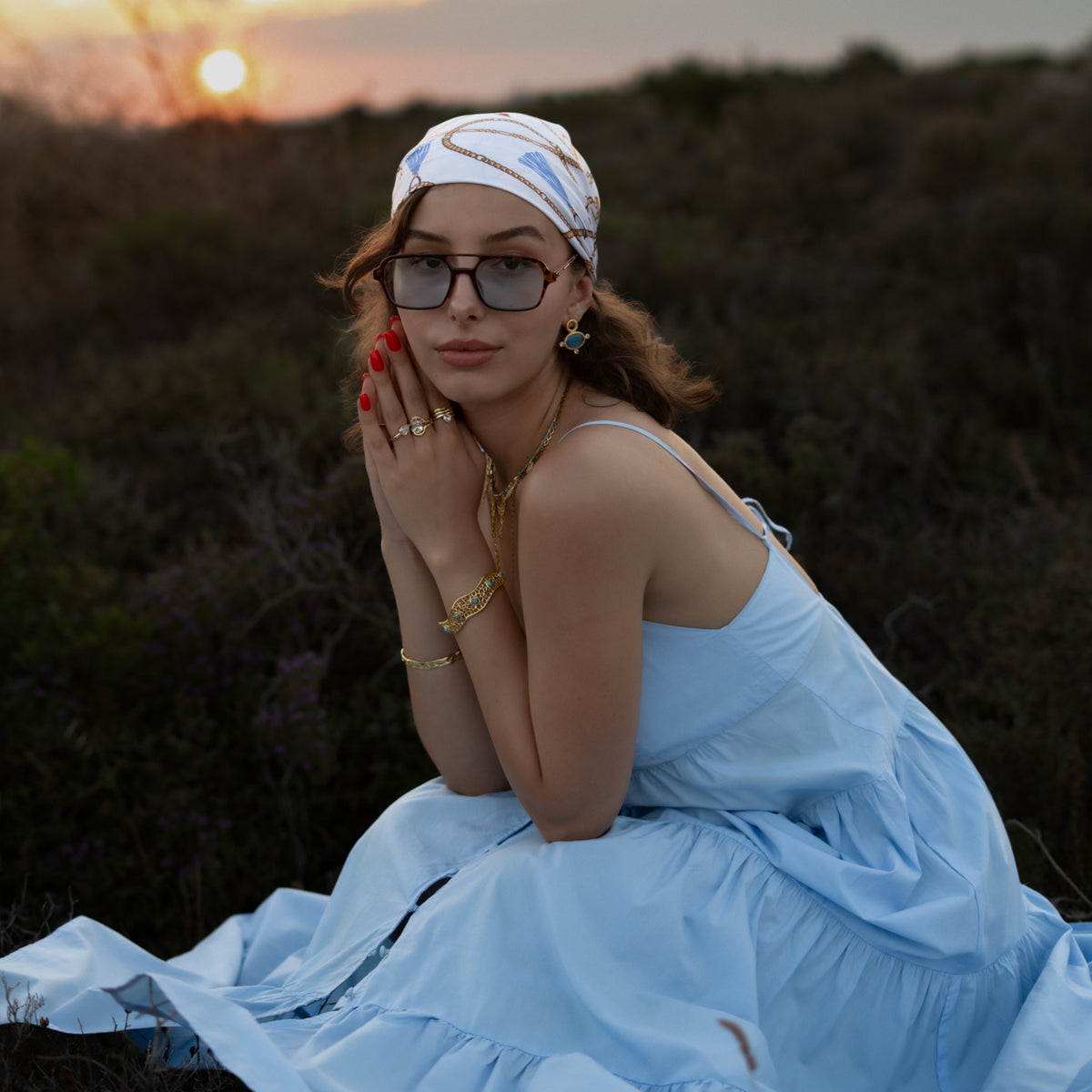 Model at sunset in a blue dress wearing the Honeycomb Lace Turquoise & Ruby Gold Cuff Bracelet