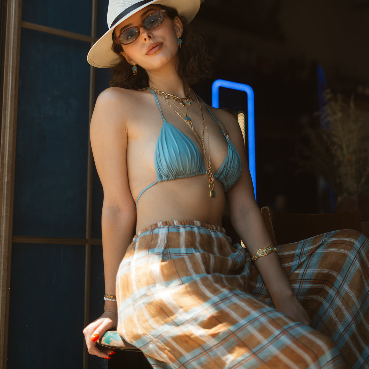 Model in a hat and plaid skirt wearing the Honeycomb Lace Turquoise & Ruby Gold Cuff Bracelet on the upper arm