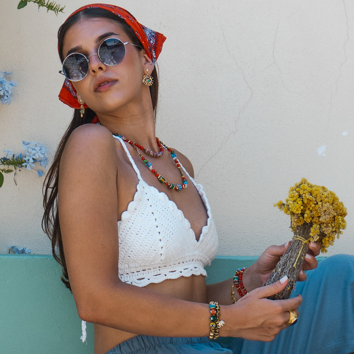 Model in a red headscarf wearing the Kept Safe Evil Eye Turquoise Gold Drop Earrings with layered Ebru Jewelry beaded necklaces