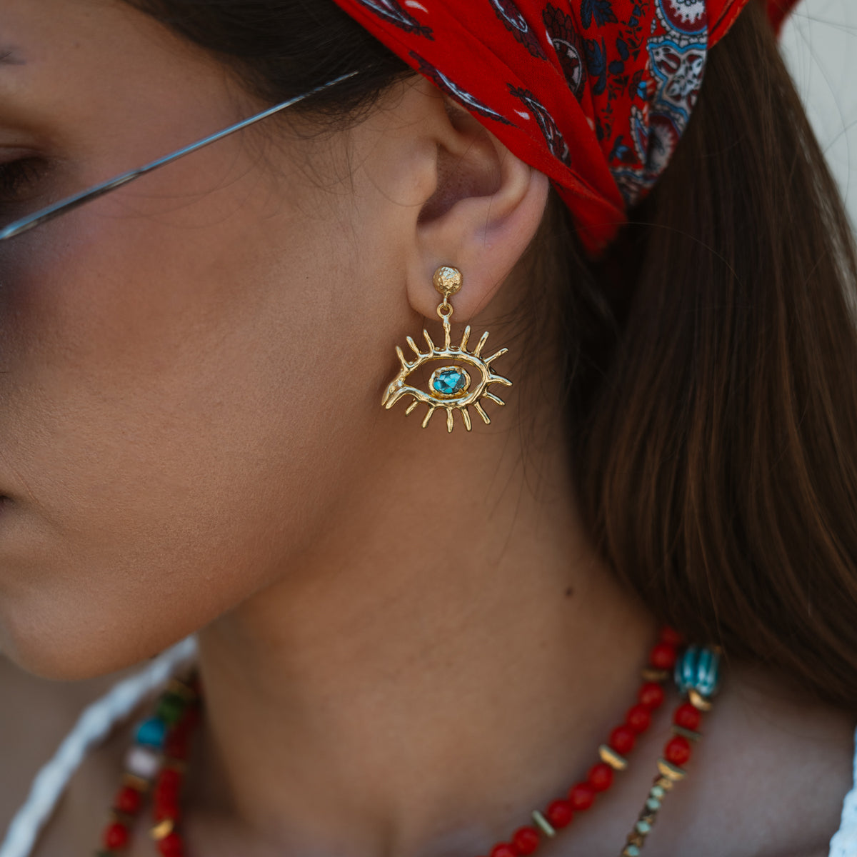 Kept Safe Evil Eye Turquoise Gold Drop Earrings worn below the ear, the turquoise eye framed by gold lashes