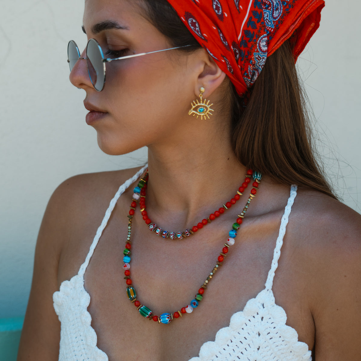 Profile view of the Kept Safe Evil Eye Turquoise Gold Drop Earrings worn with layered coral and turquoise beaded necklaces
