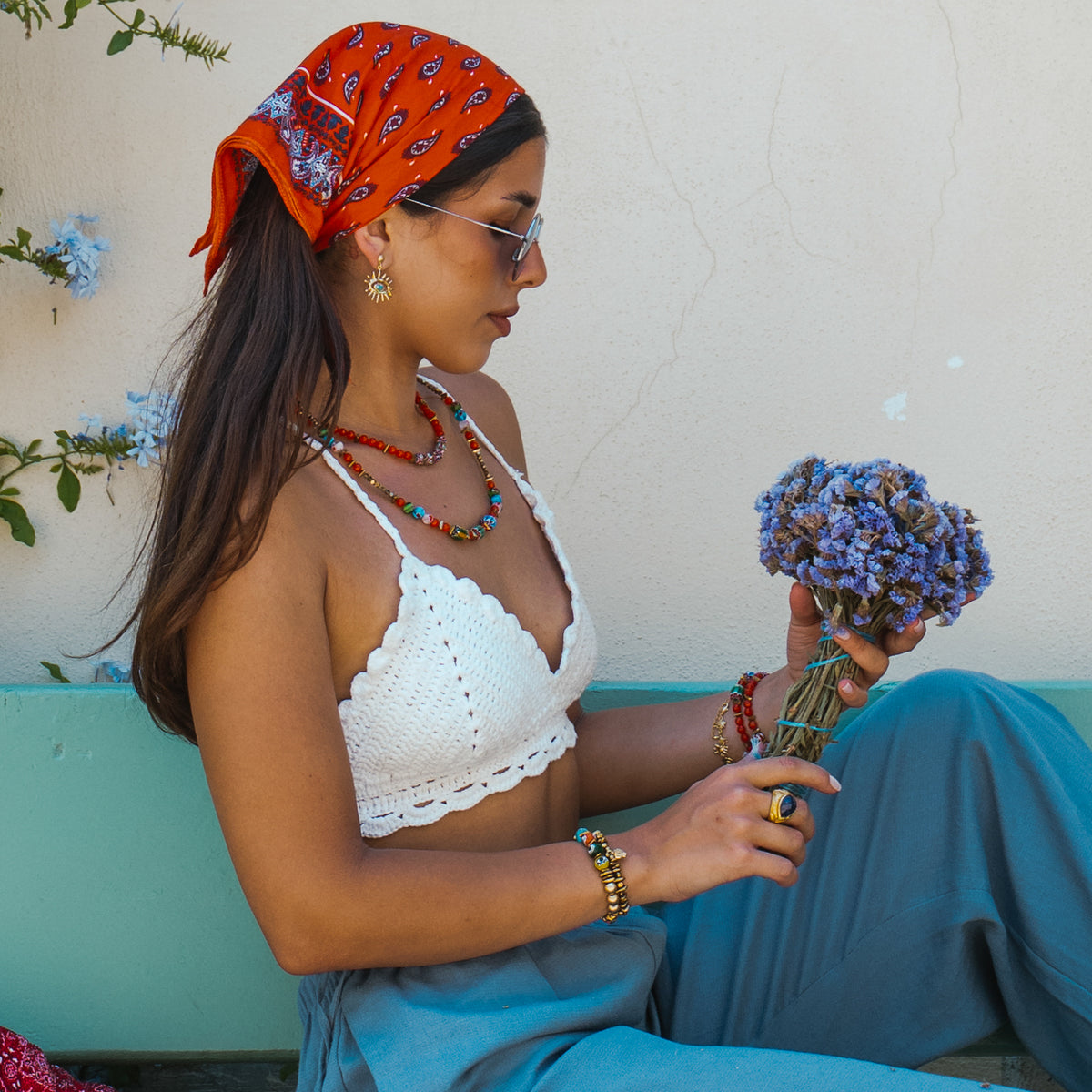 Model holding lavender while wearing the Kept Safe Evil Eye Turquoise Gold Drop Earrings