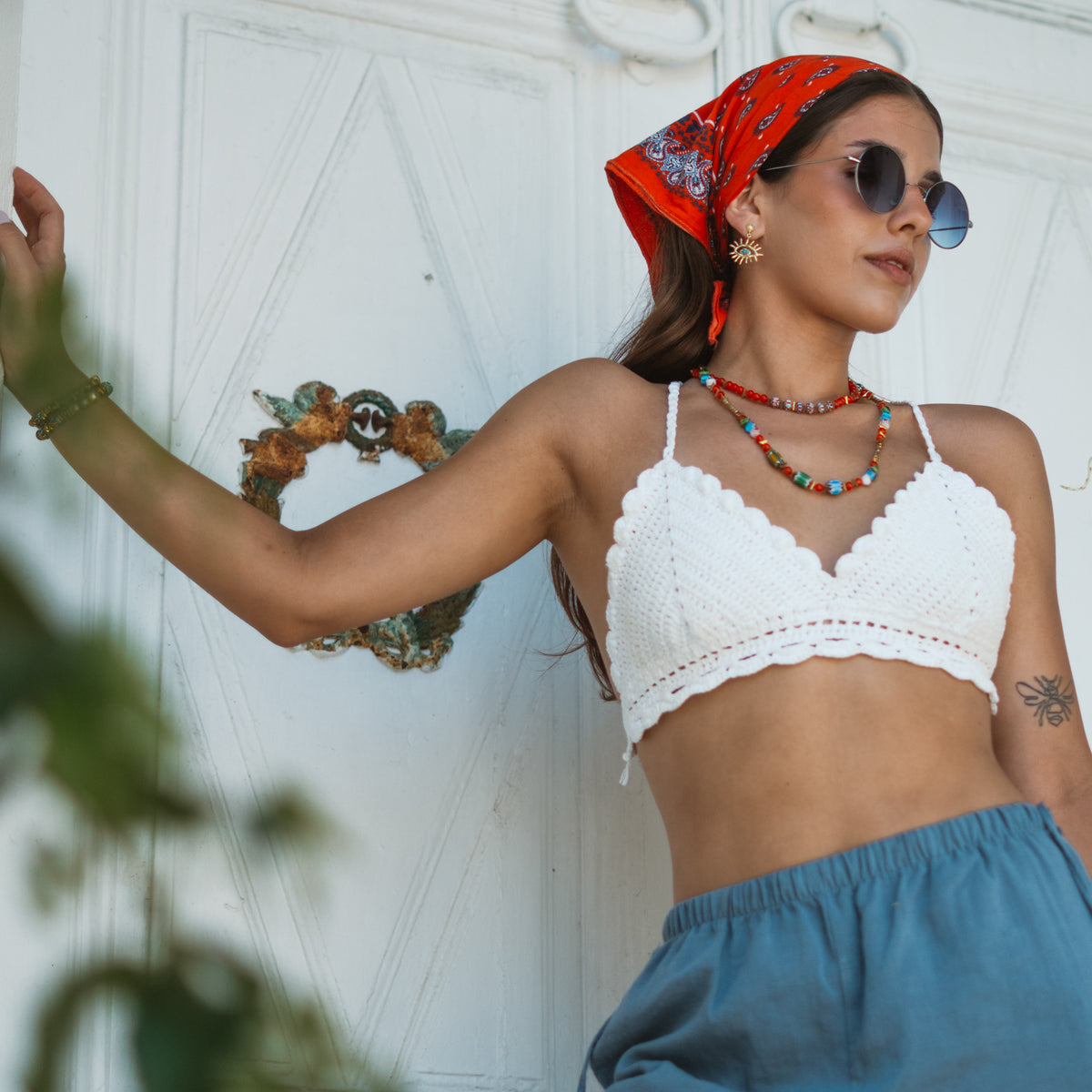 Model at a white doorway wearing the Kept Safe Evil Eye Turquoise Gold Drop Earrings with a beaded necklace