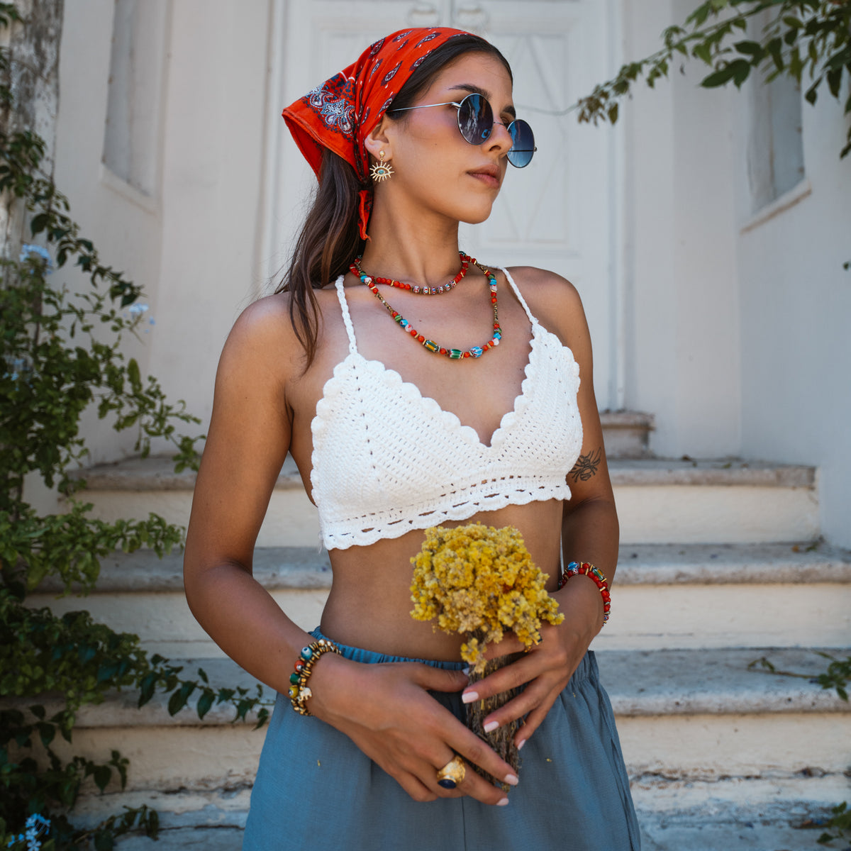 Model on stone steps wearing the Kept Safe Evil Eye Turquoise Gold Drop Earrings with beaded necklaces and bracelets