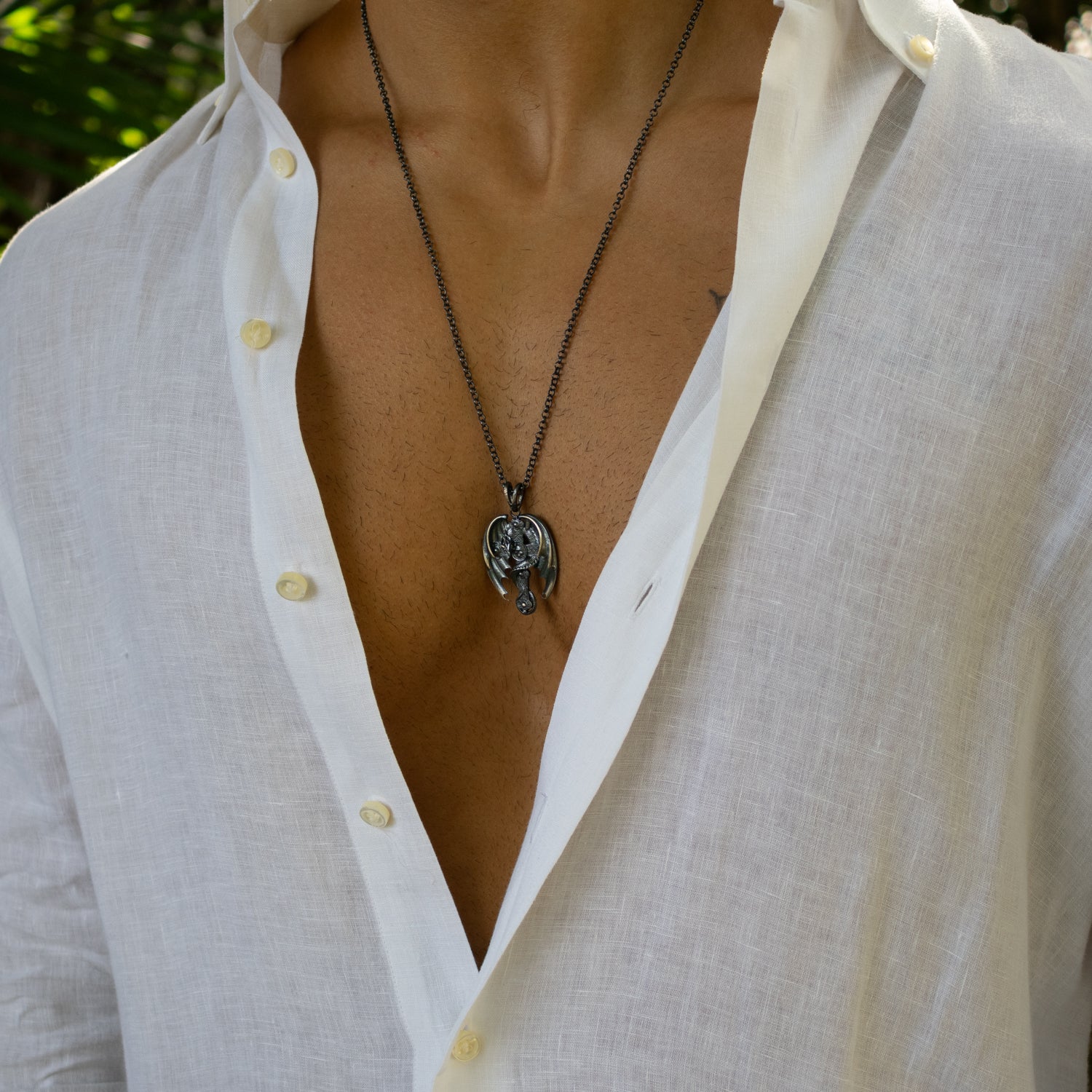 Sterling silver necklace with intricately detailed dragon wrapped around cross pendant, rhodium finish, textured scales, strong chain, bold style.