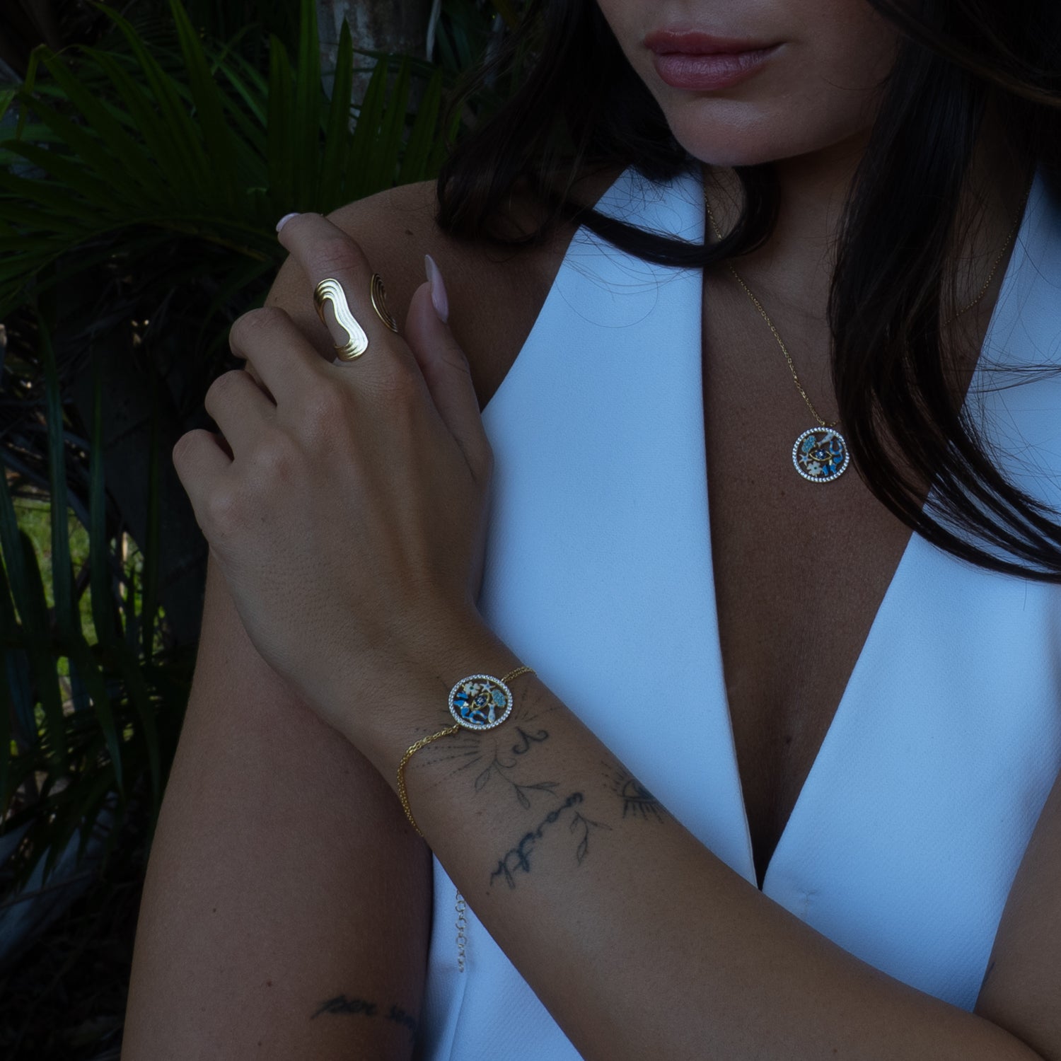 Woman wearing a white top with visible jewelry against a natural background