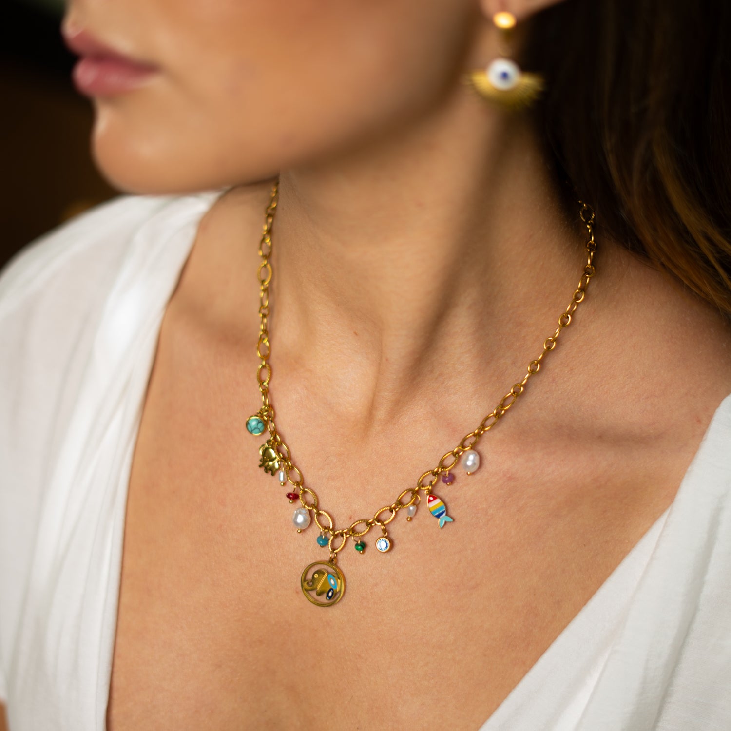 Handmade gold-plated charm necklace with elephant for strength and fish for abundance, accented with pearls and enamel