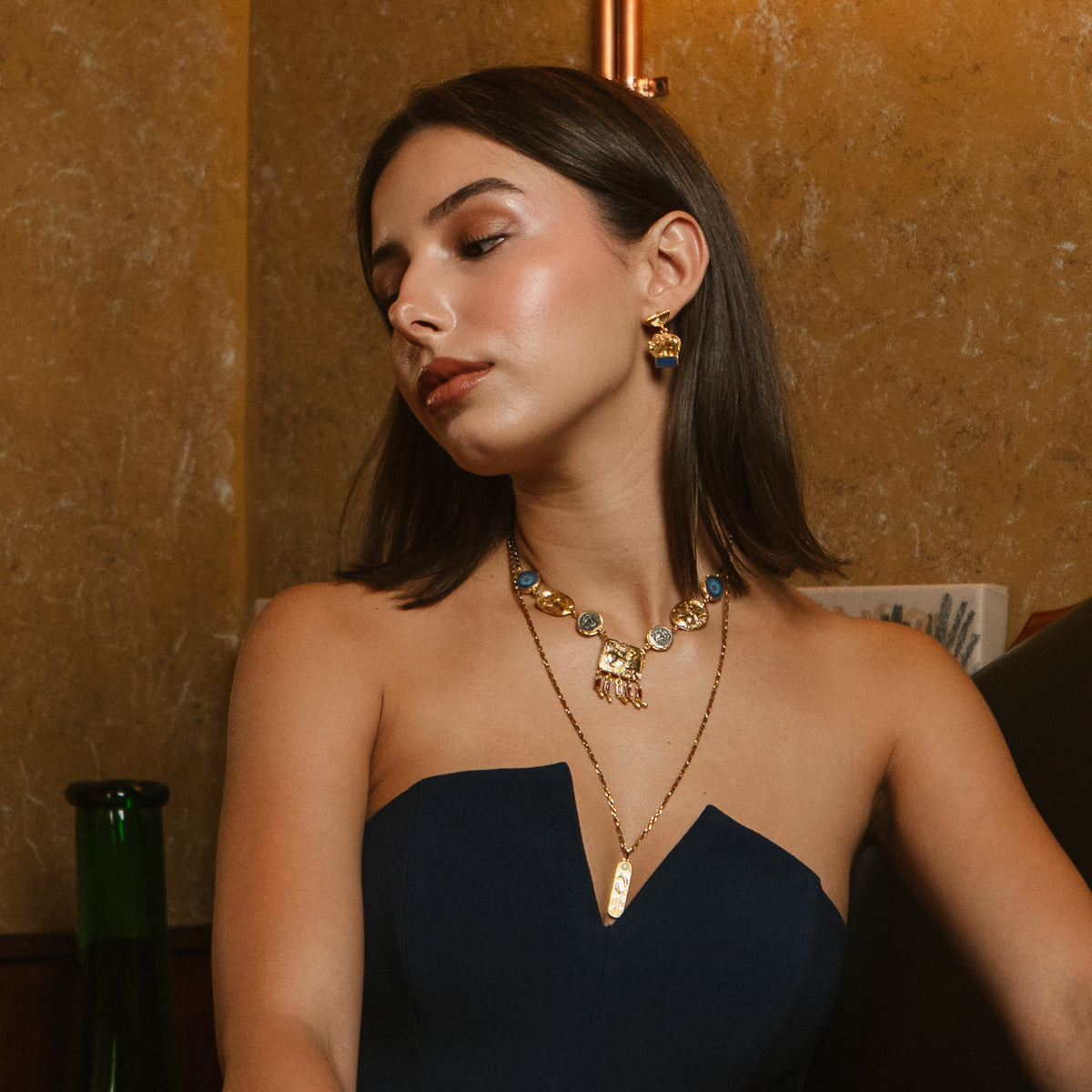 Model seated wearing the Lucky Elephant Lapis Lazuli Gold Drop Earrings with layered Ebru Jewelry necklaces