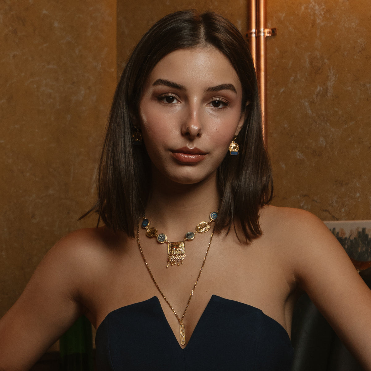 Front view of a model wearing the Lucky Elephant Lapis Lazuli Gold Drop Earrings with a gold and lapis collar necklace