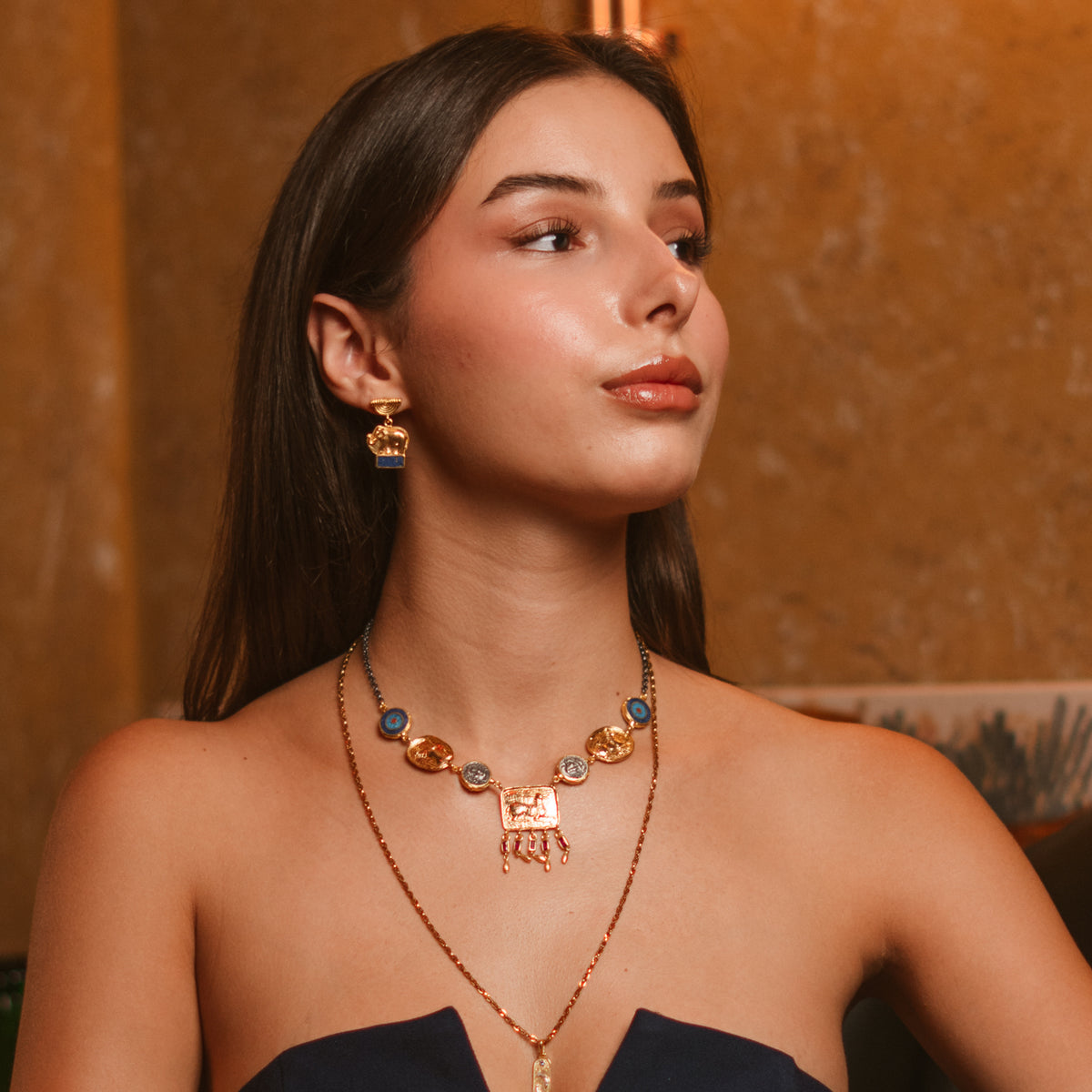 Model in a navy dress wearing the Lucky Elephant Lapis Lazuli Gold Drop Earrings with a layered gold necklace