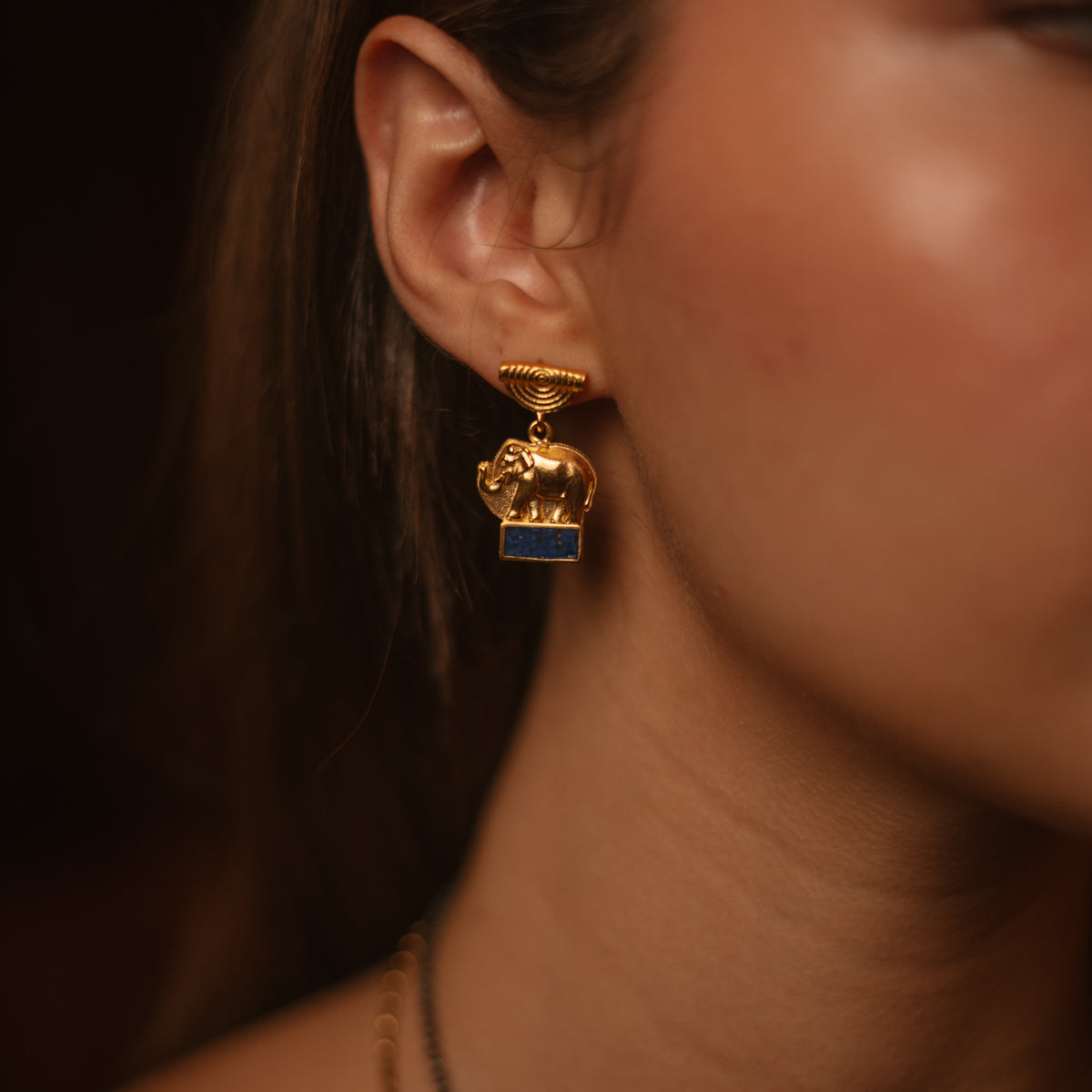 Lucky Elephant Lapis Lazuli Gold Drop Earrings worn below the ear, the half sun disc top sitting on the lobe