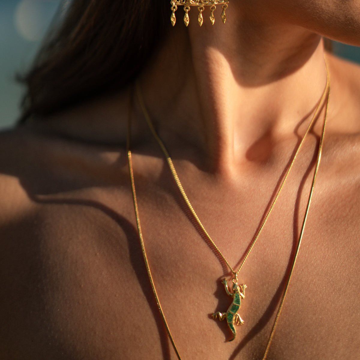 Close up of the green malachite gecko pendant worn at the collarbone with a longer gold chain
