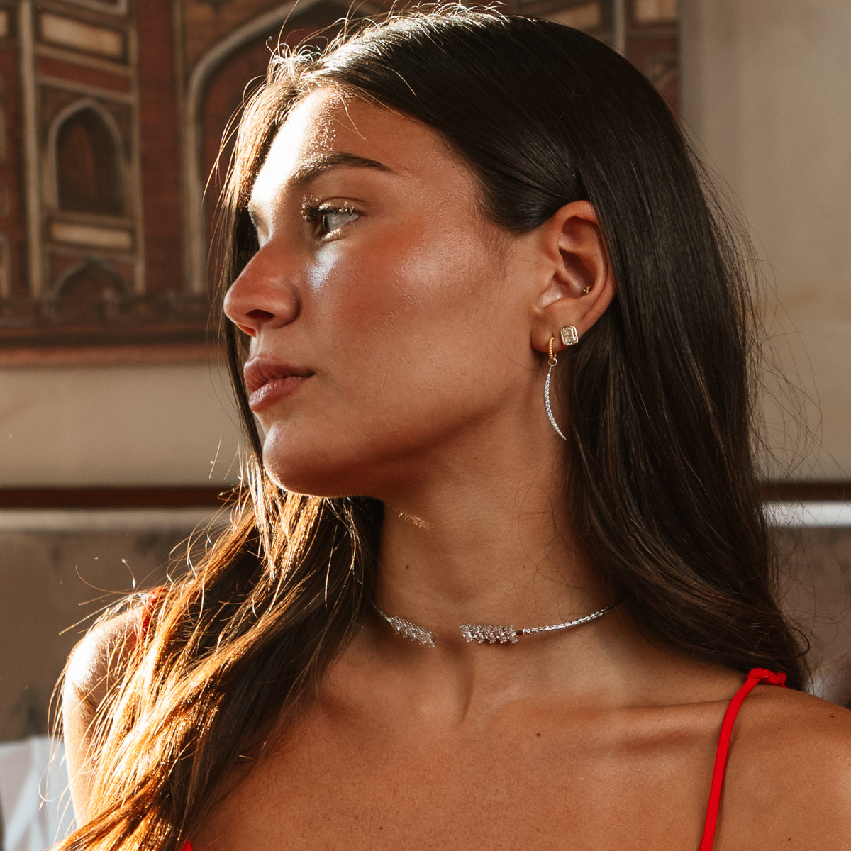 Woman in profile wearing the Luminous Arc Mixed Metal Pave Zircon Drop Earrings and a silver pave choker