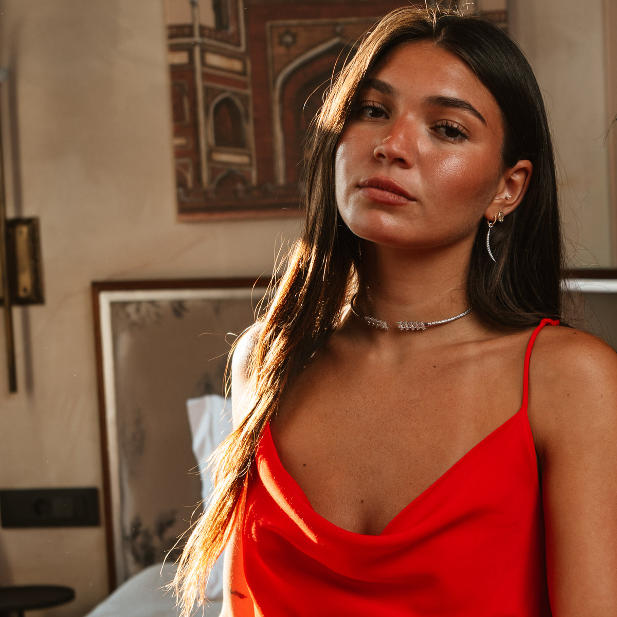 Model in a red slip top wearing the Luminous Arc drop earrings with a silver choker