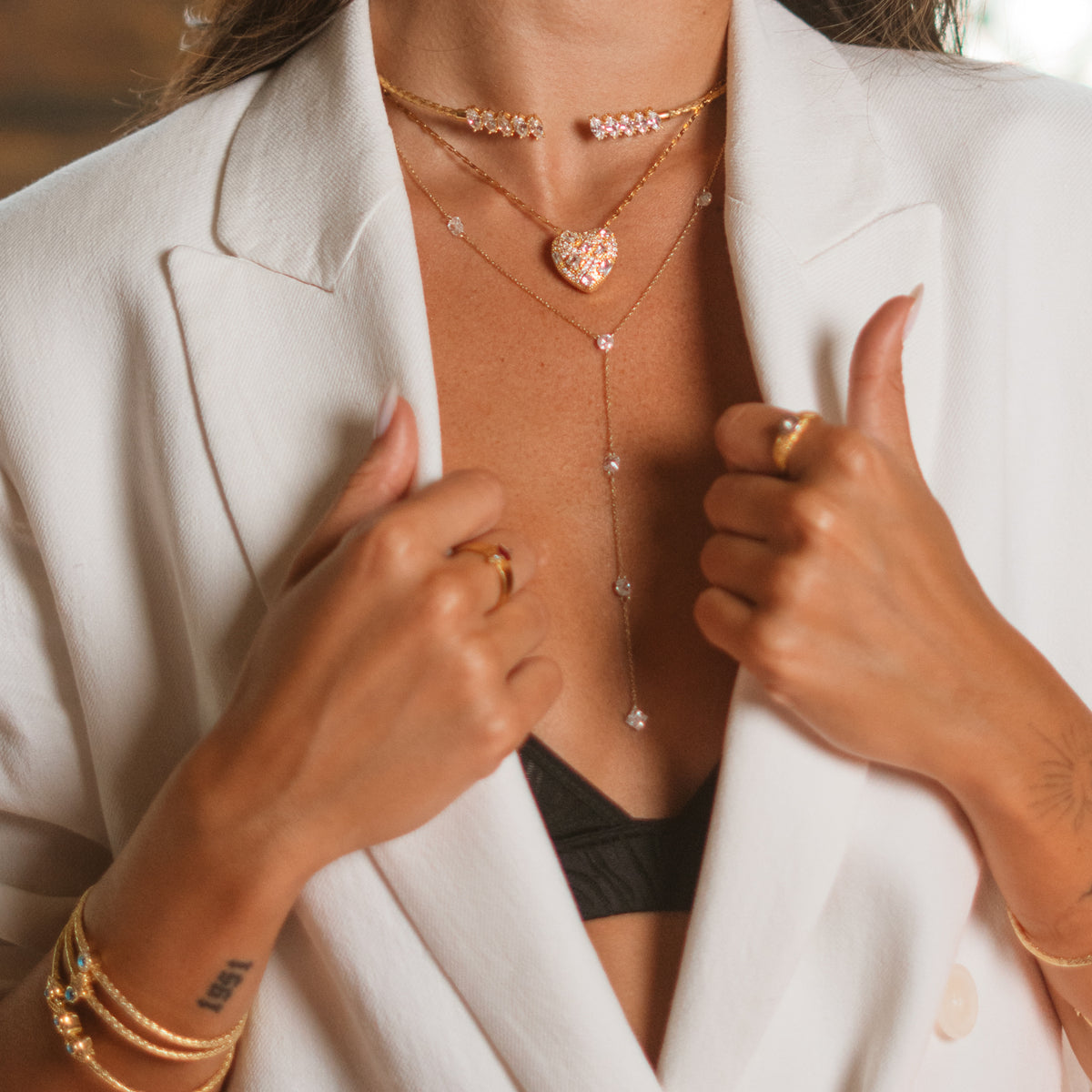 Close up of a woven gold vermeil marquise choker worn at the throat over layered gold necklaces