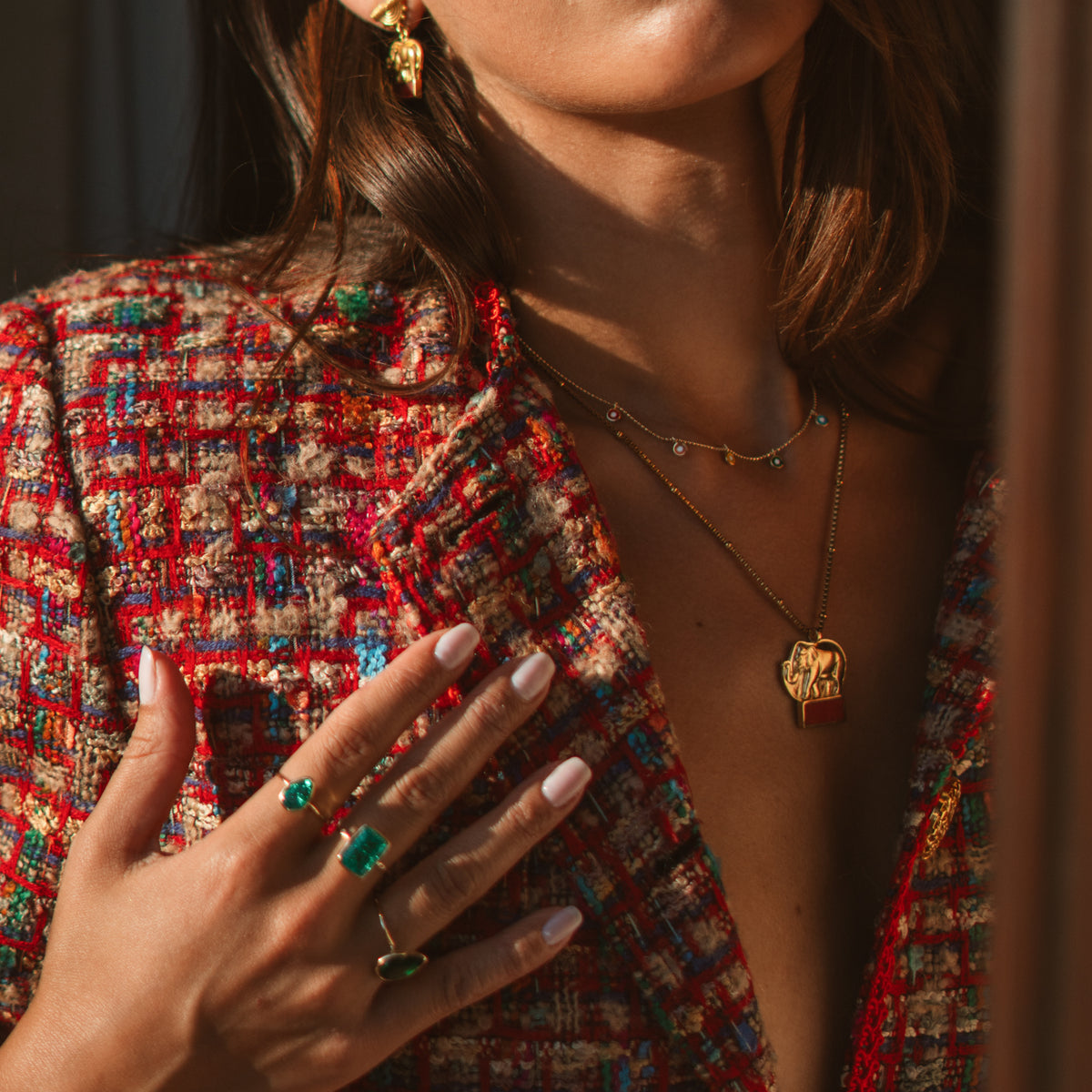 Model in a colorful tweed jacket wearing the dainty multicolor evil eye charm gold necklace with layered chains and rings