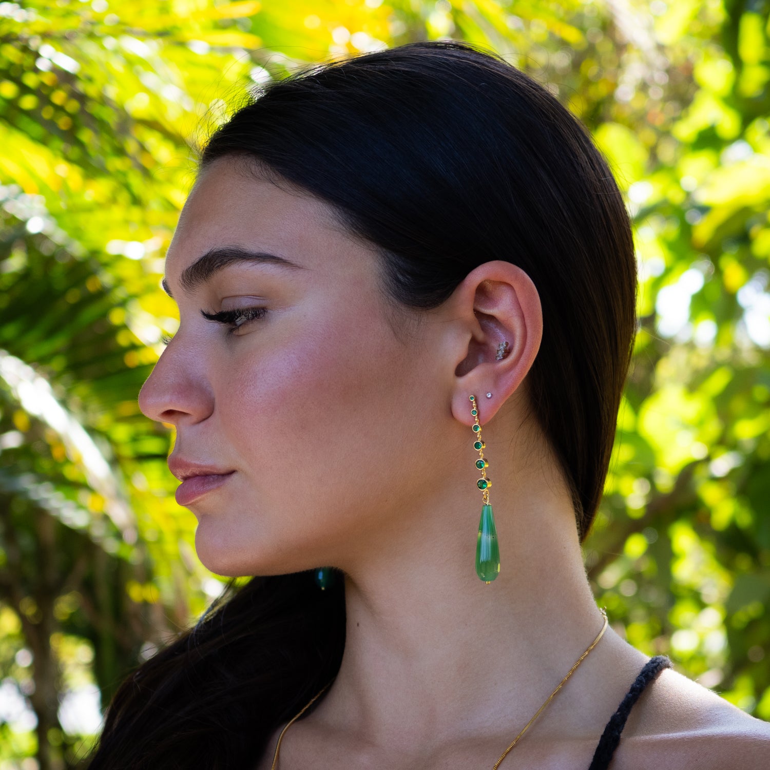 Close-up of gold-plated jade earrings with green crystal detail for grounding and balance

