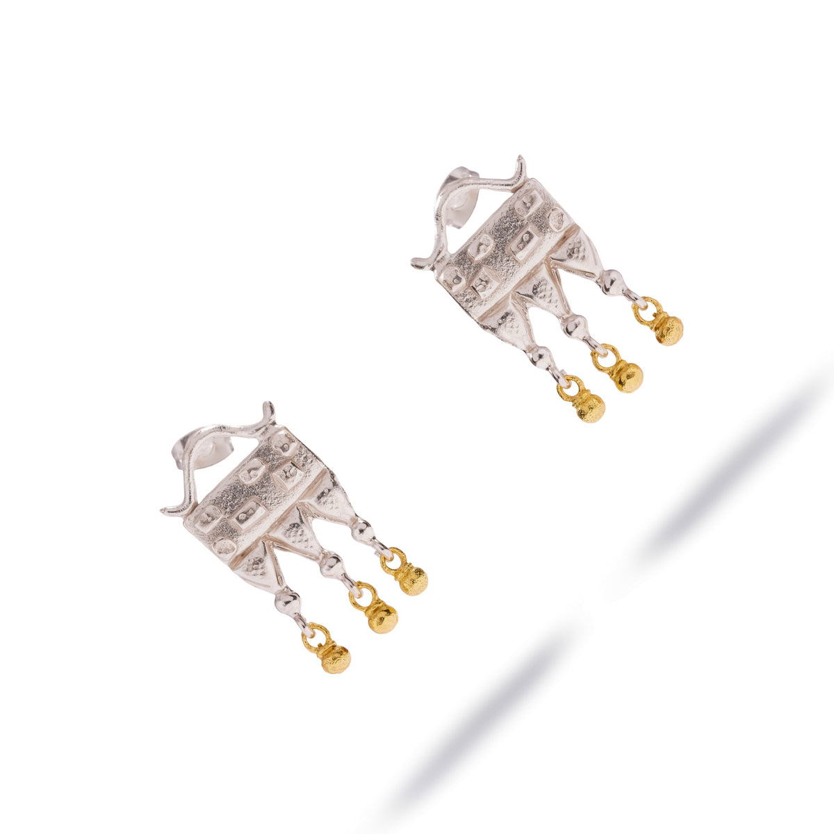 Mystic Temple earrings laid diagonally, three silver points ending in granulated gold plated beads