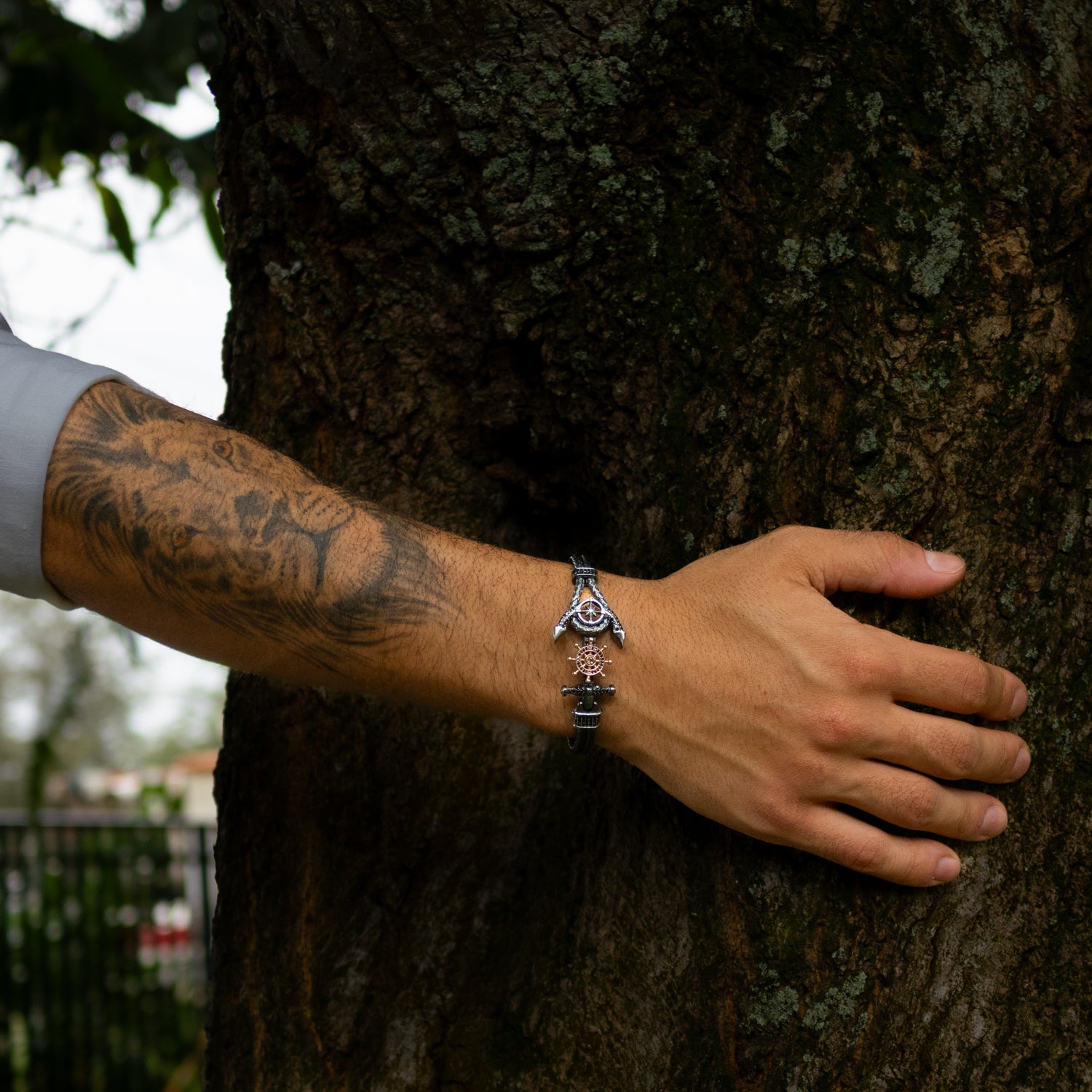 Men’s bracelet in sterling silver and rose gold, anchor and ship wheel charms, black diamond accents, woven band, handcrafted nautical style.