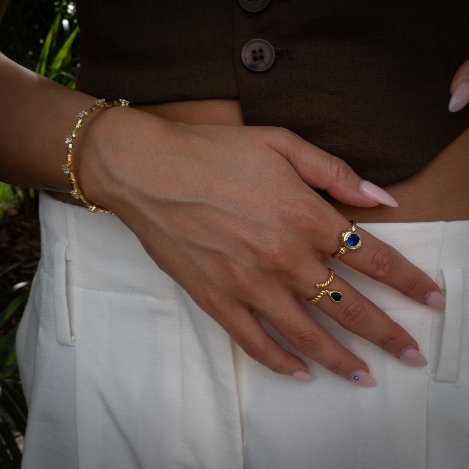Close-up of a hand wearing gold rings and a bracelet on a white background