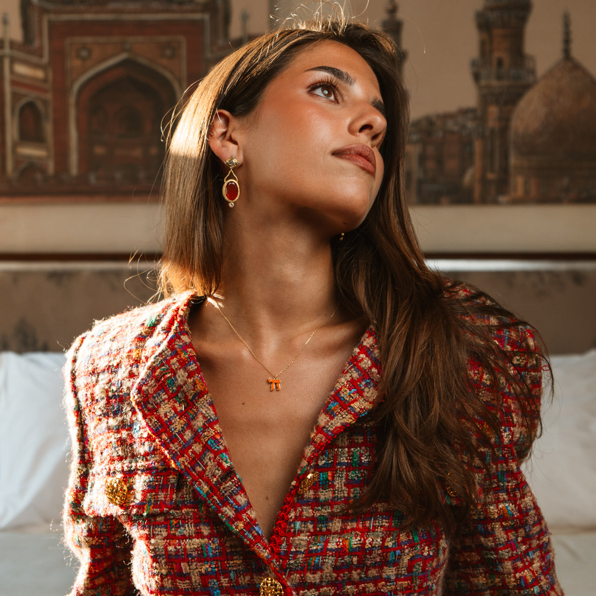 Model in a red tweed jacket wearing the Orange Chai Symbol Gold Pendant Necklace