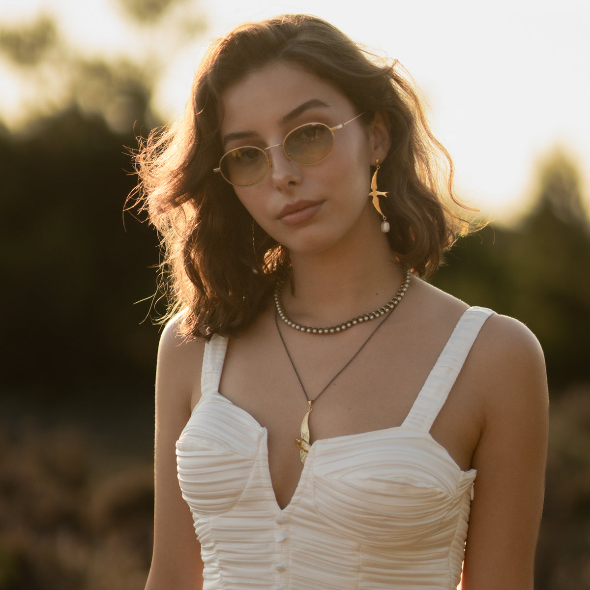 Model in warm evening light wearing the antique gold pearl tennis necklace close to the throat
