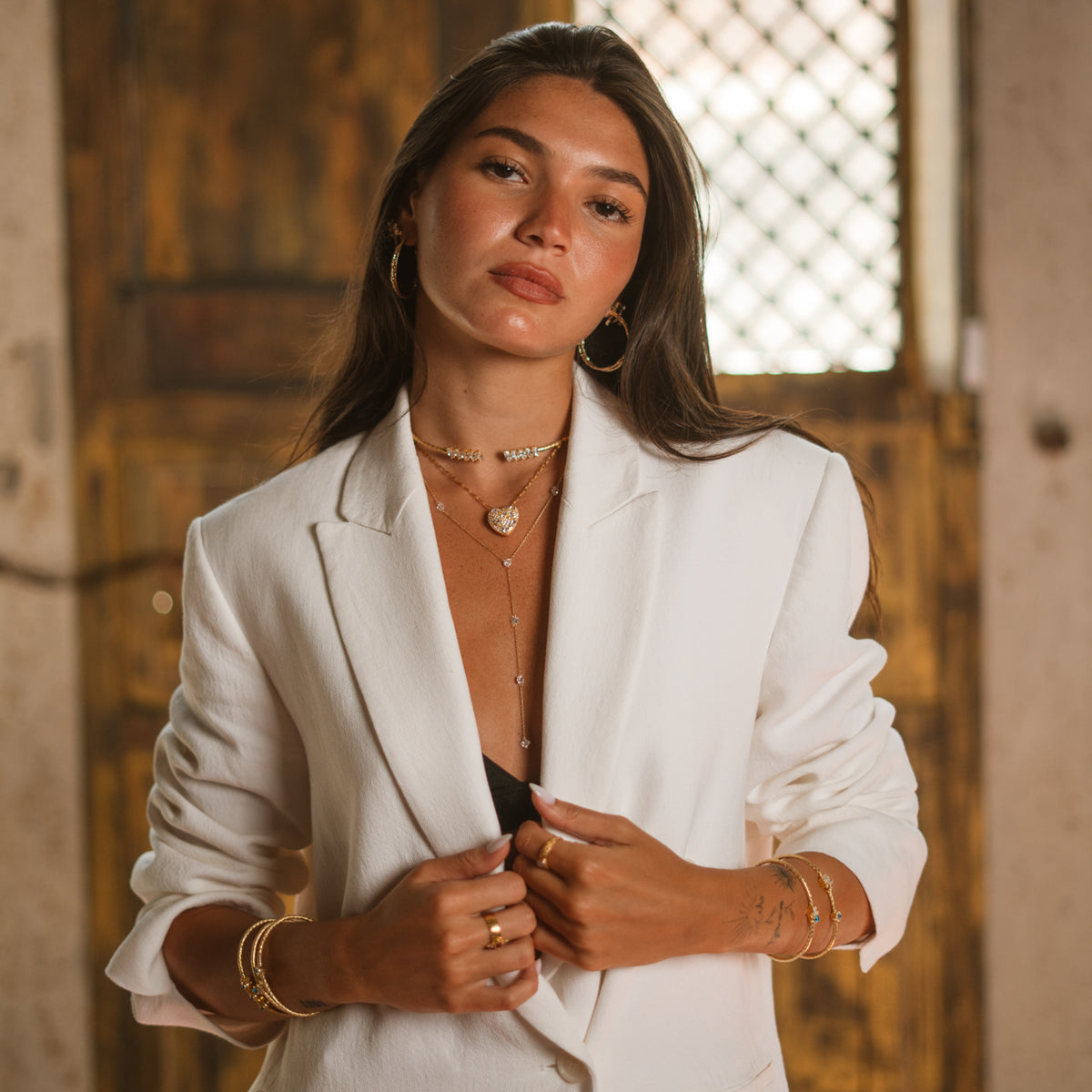 Model in a white blazer wearing the Princess Cut Zircon Gold Lariat Necklace with layered gold necklaces
