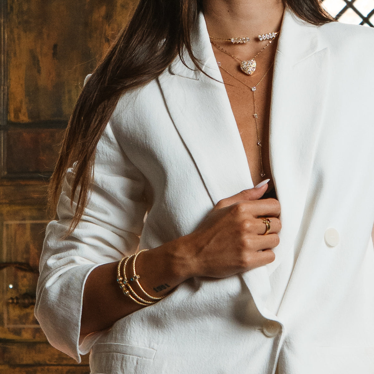 Close up of the zircon gold lariat necklace falling down the neckline under a white blazer