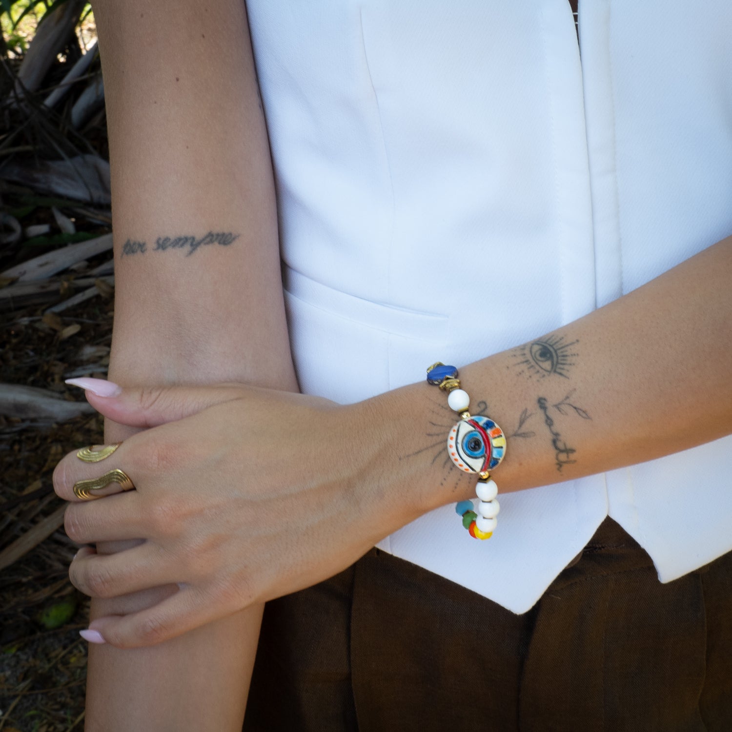 Reversible evil eye bracelet worn on wrist with hand-painted ceramic focal bead and rainbow crystal beads, paired with complementary jewelry