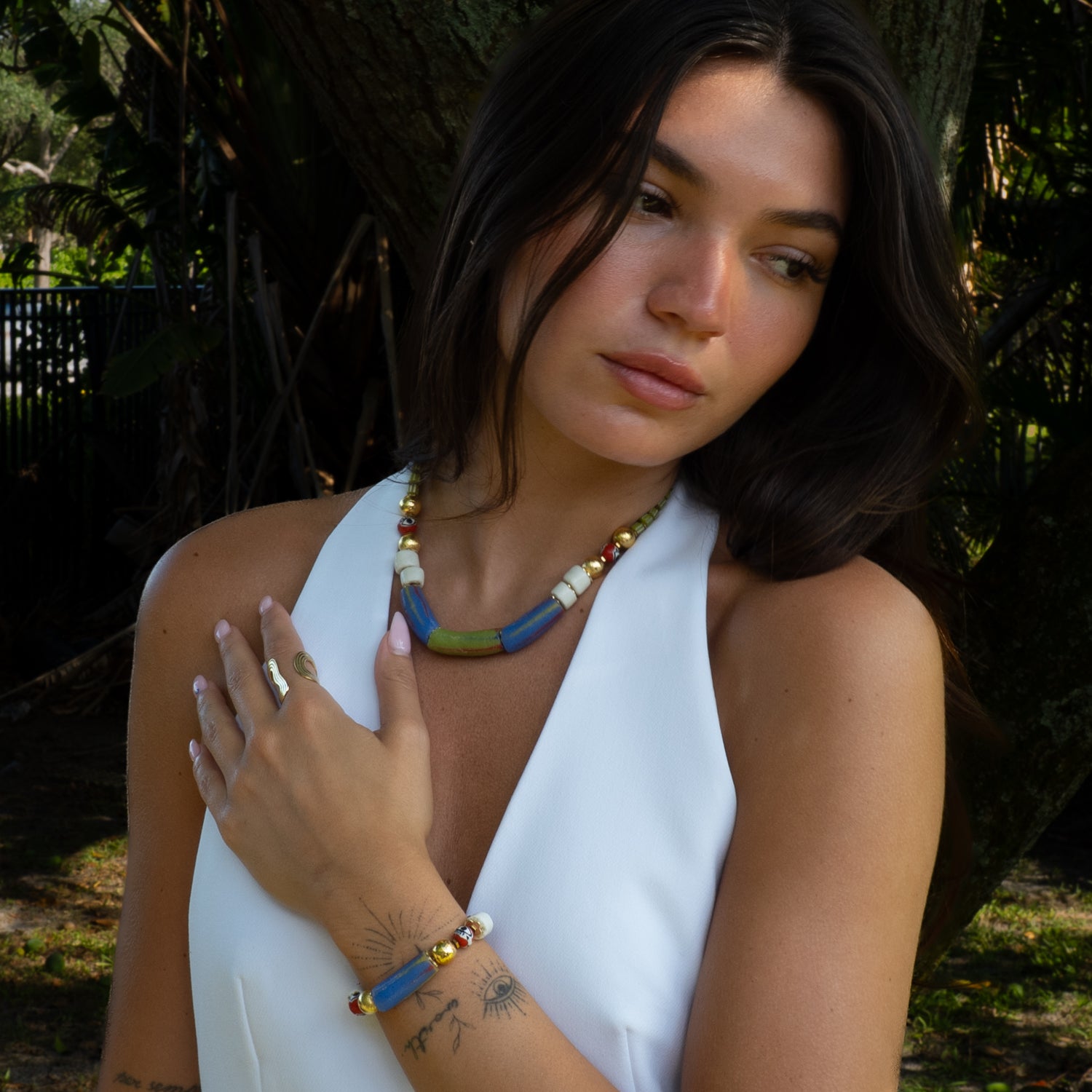 Woman wearing sacred African trade bead evil eye talisman bracelet with white halter top