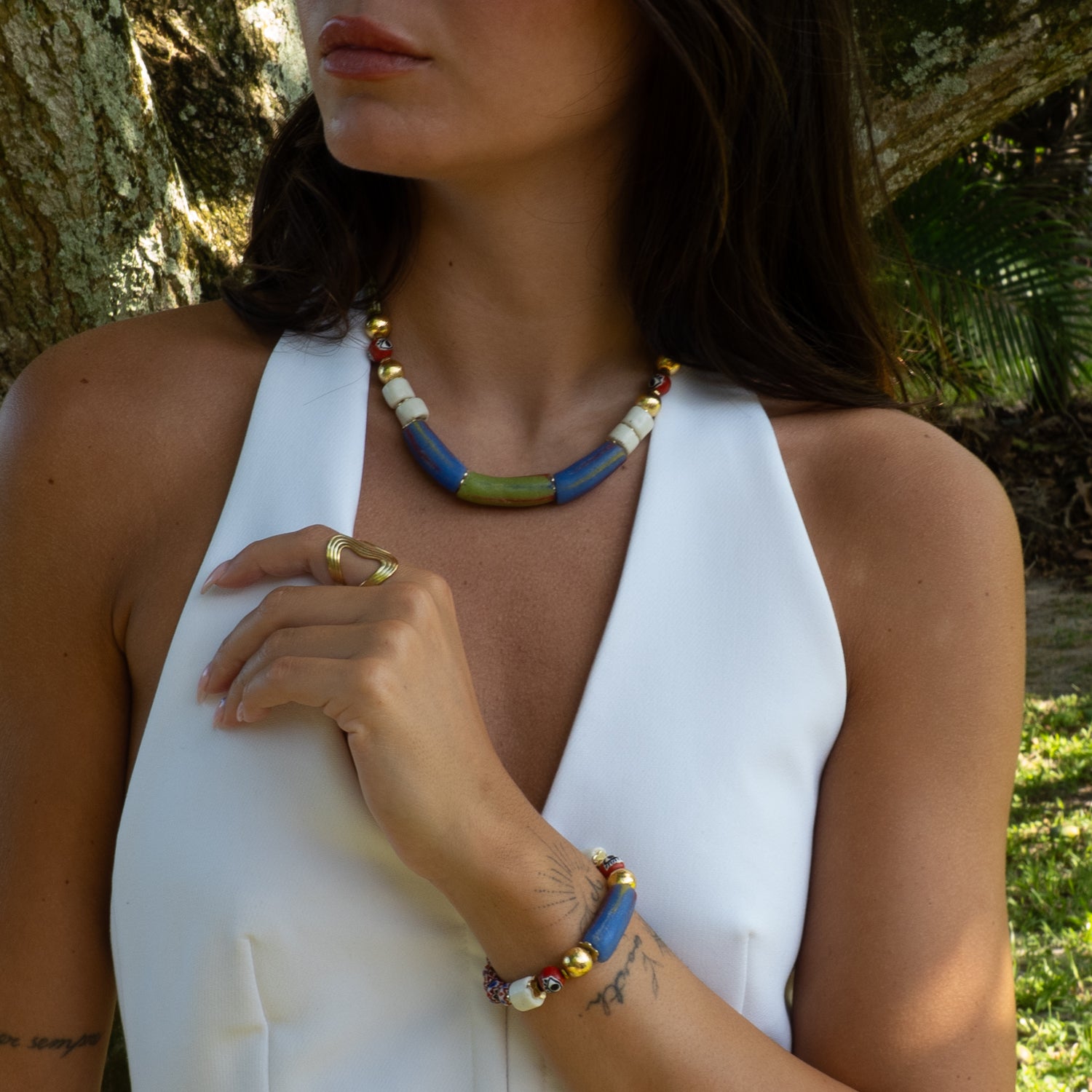 Model wearing handmade African trade bead bracelet styled with statement necklace
