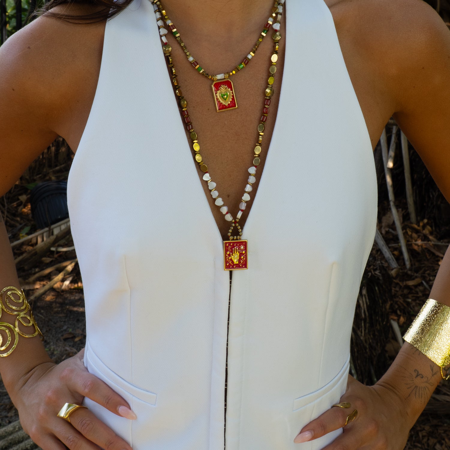 Woman wearing layered sacred hand evil eye pearl necklace with white halter top