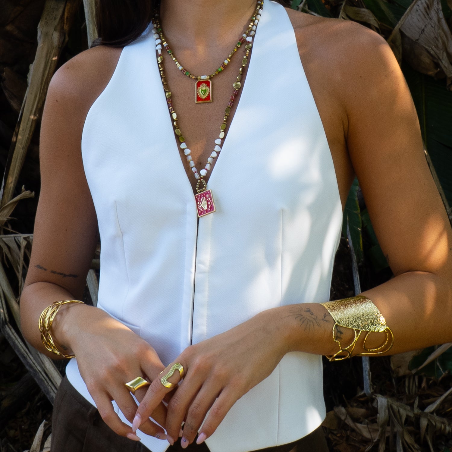 Close view of red enamel evil eye hand pendant necklace styled on a white outfit